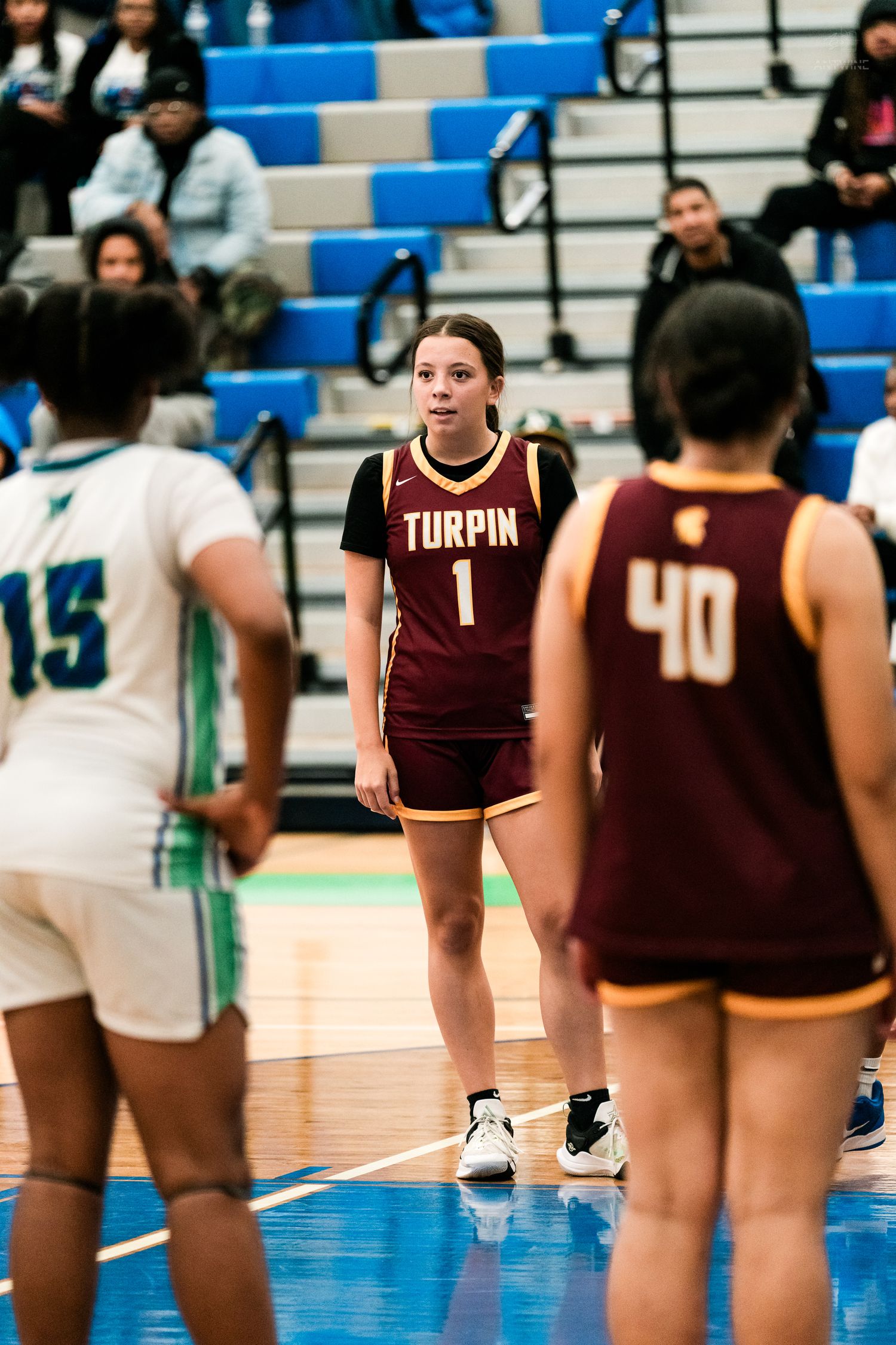 Turpin High School female basketball player number 1 stands ready during a girls high school basketball game indoors.