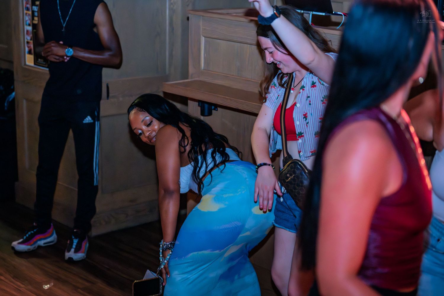 Woman in blue dress dancing at a dimly lit nightclub party event.