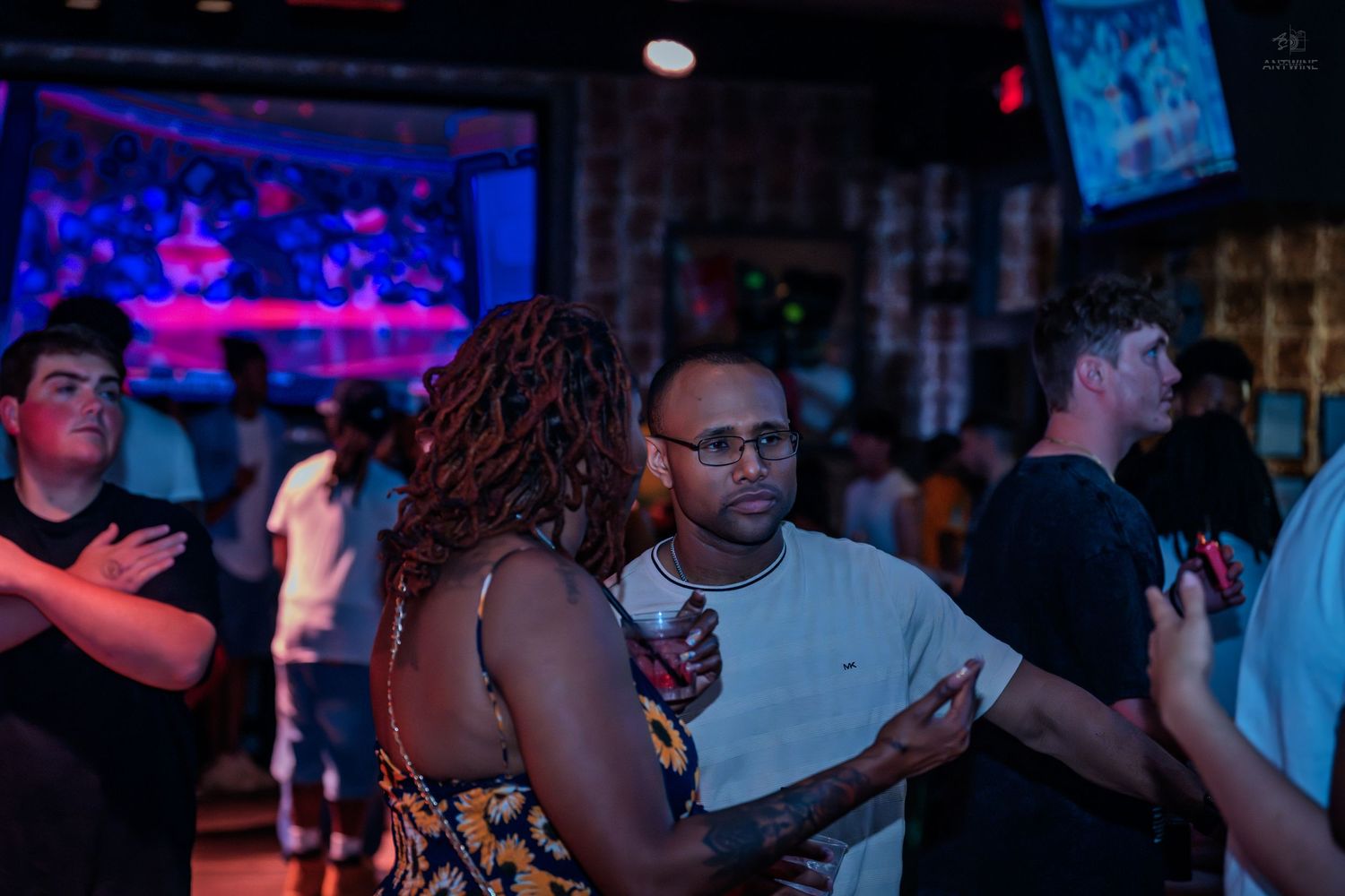 Couple dancing closely together in a lively nightclub with blue neon lights.