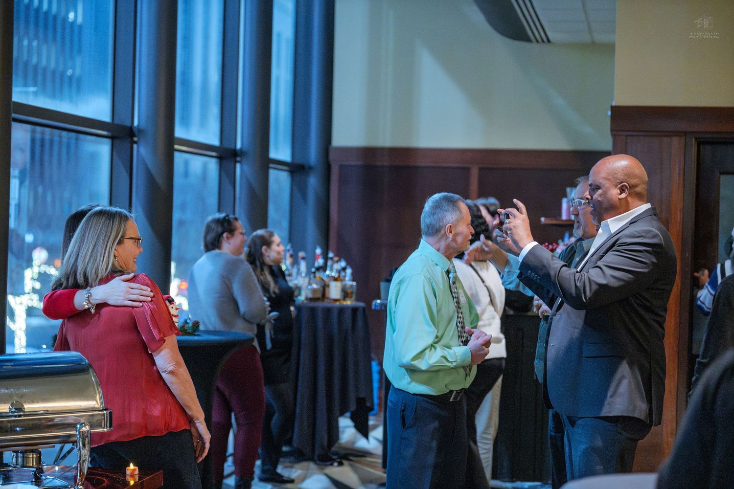 Guests mingle and take photos at an elegant indoor corporate networking event reception.