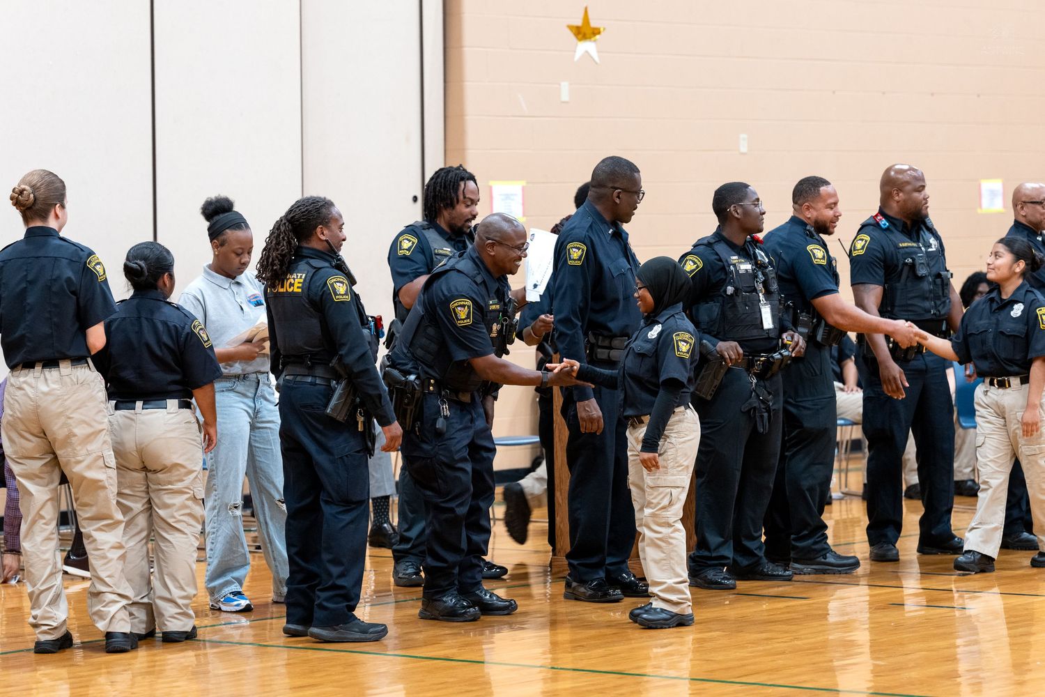 A line of police officers in uniform standing in a gymnasium during a law enforcement event.