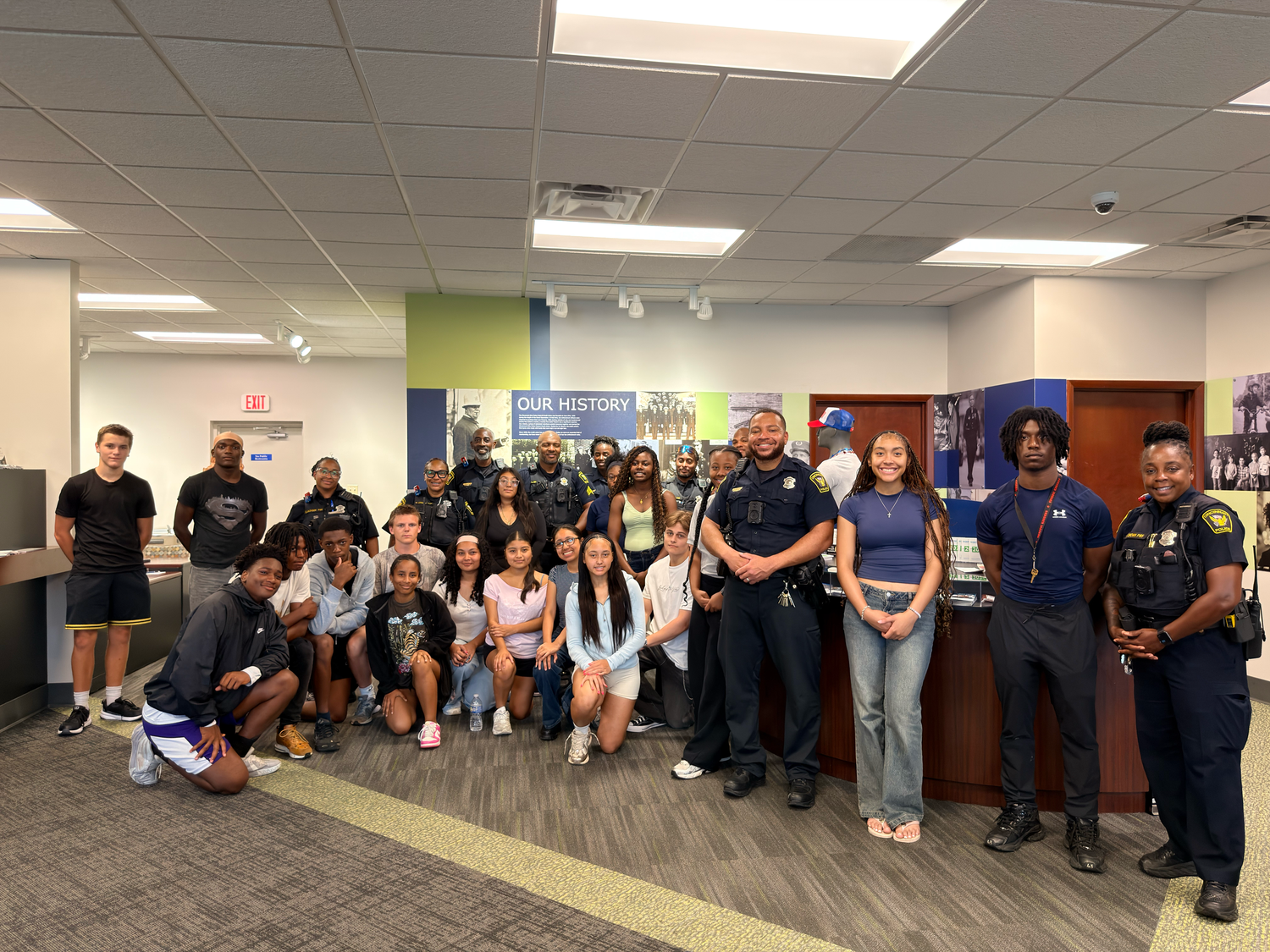 Group of students and police officers posing together indoors at a community engagement event.