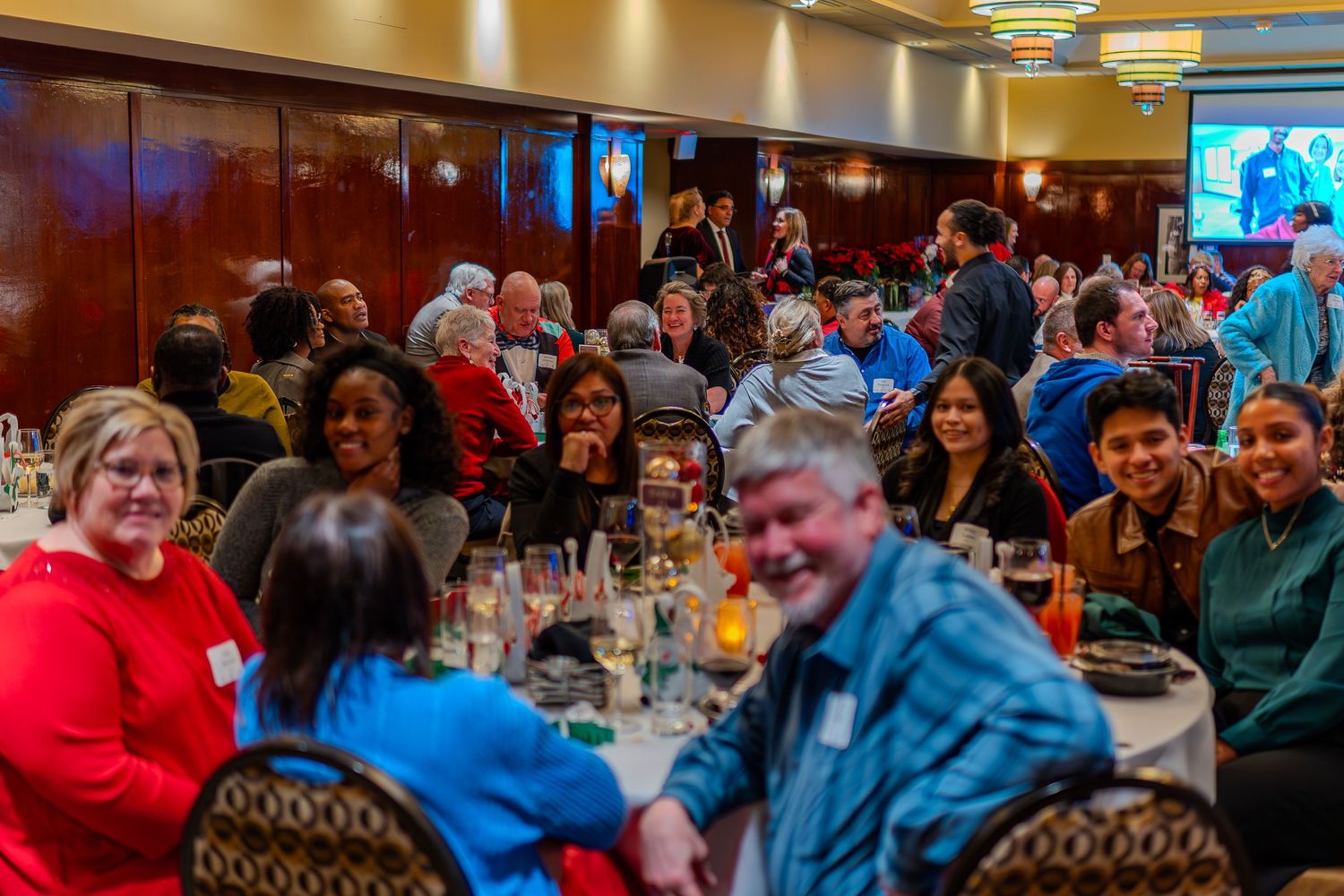 Diverse group of people enjoying a large banquet dinner event in an elegant ballroom with warm lighting.