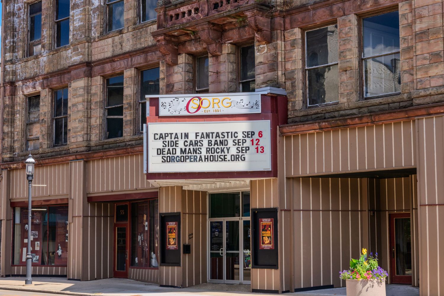 Vintage Sorg Opera House brick building with white marquee displaying upcoming shows and events.