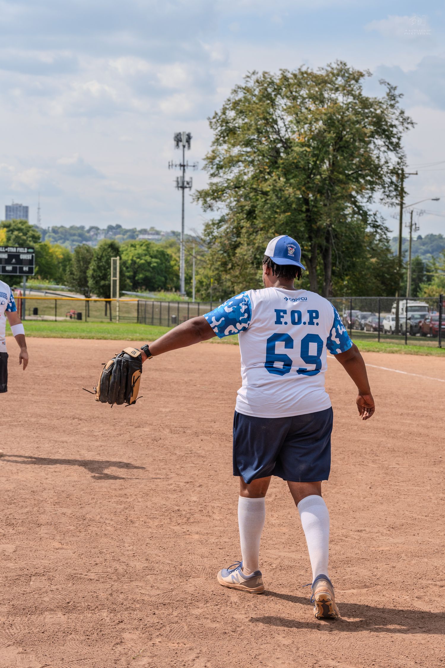 Baseball player wearing FOP jersey number 69 throws ball on dirt field during outdoor game on sunny day.