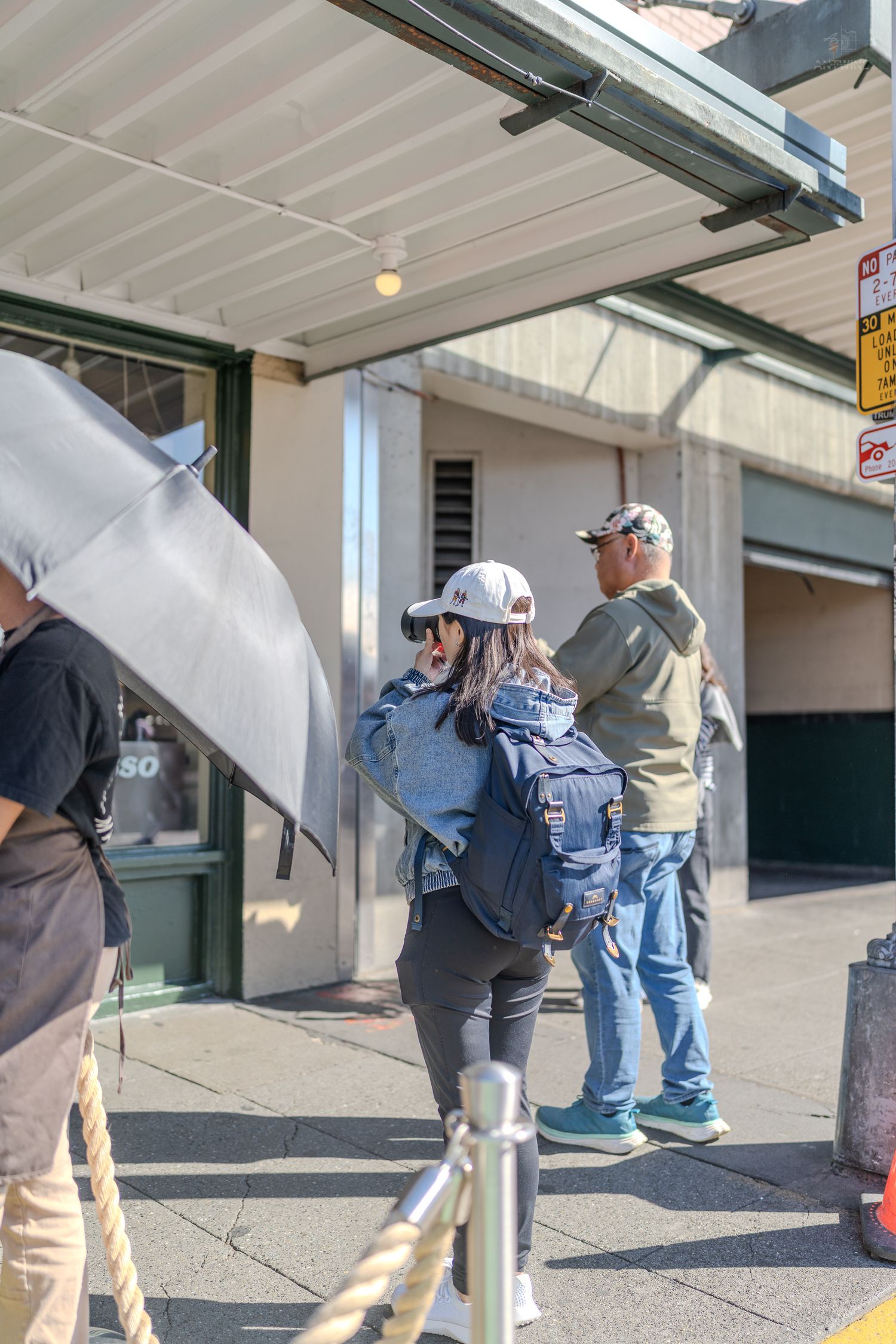 Tourists waiting in line outside a building at Seattle's Pike Place Market on a bright sunny day.
