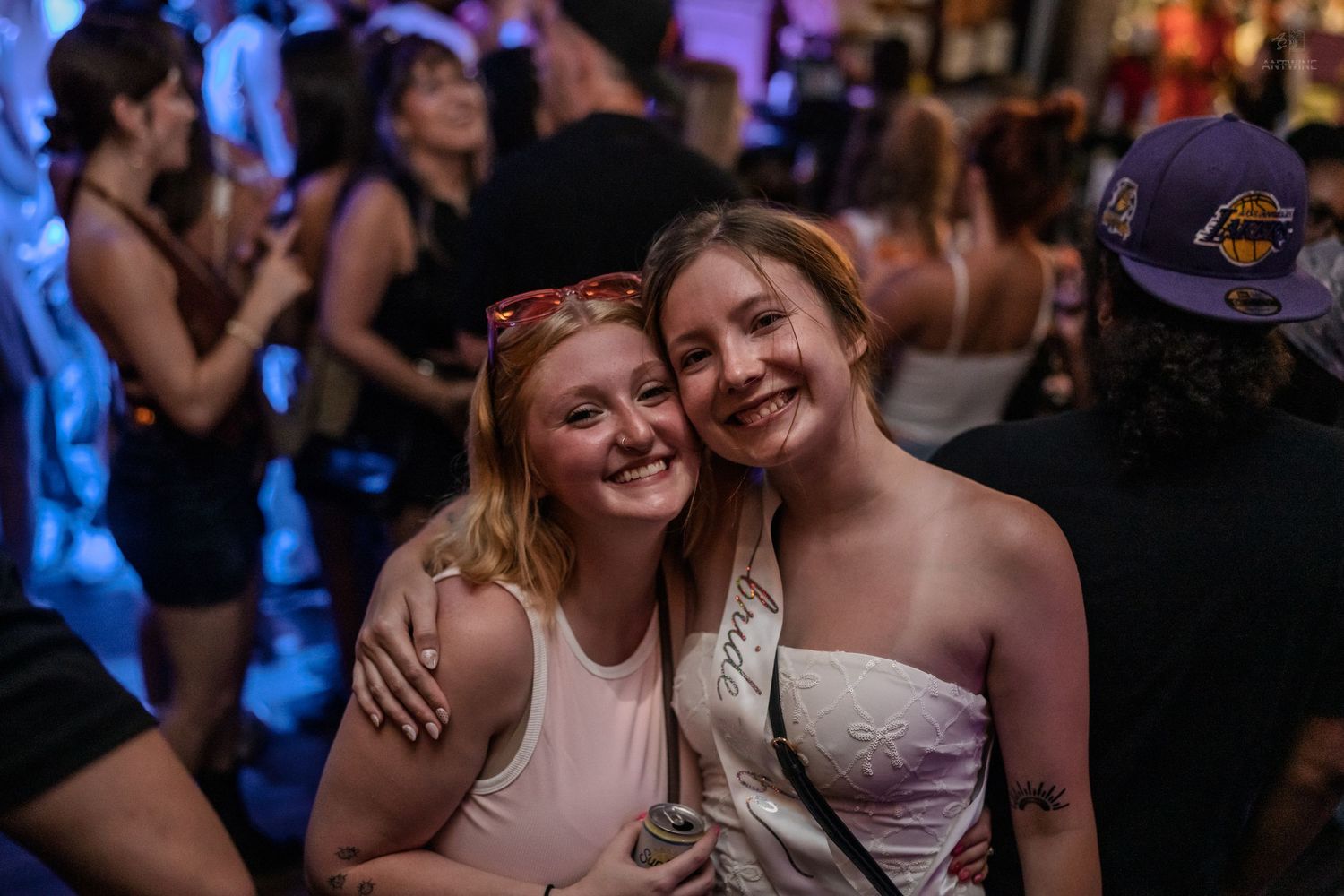 Two smiling young women posing together at a lively nightclub event.