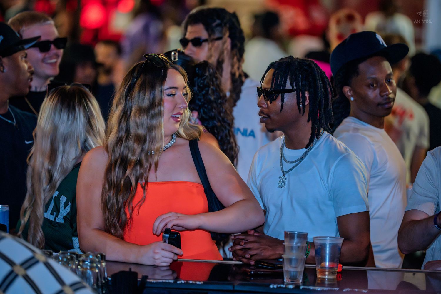 Young couple smiling together at a lively bar with drinks on the counter.