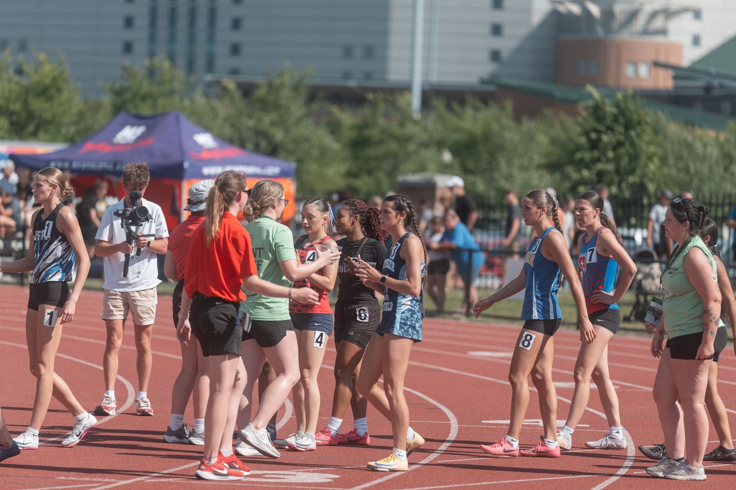 Female track and field athletes congratulate each other on the track after completing a relay race competition.