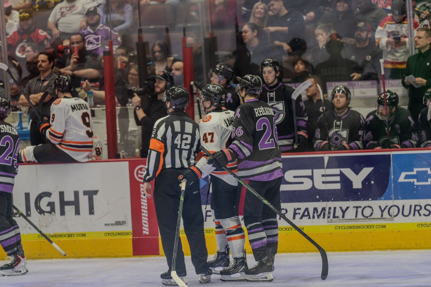 A referee separates players from two hockey teams during a tense moment in a hockey game.