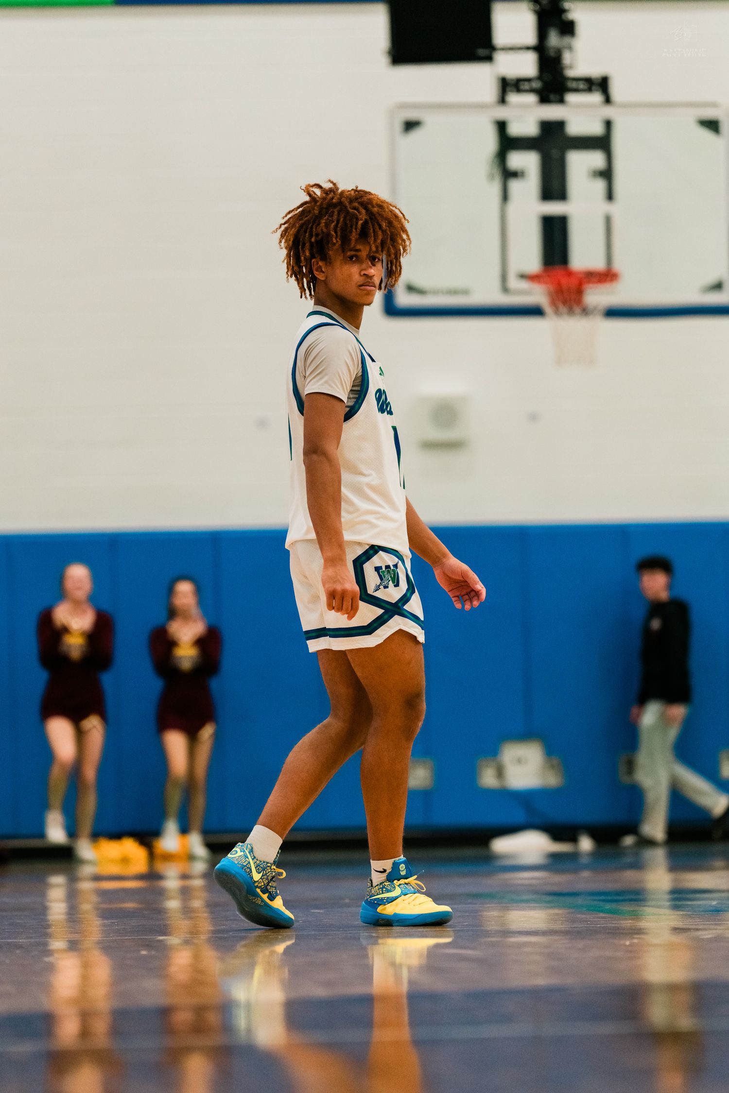 A Warriors basketball player with curly hair walks confidently across the hardwood court during a game.