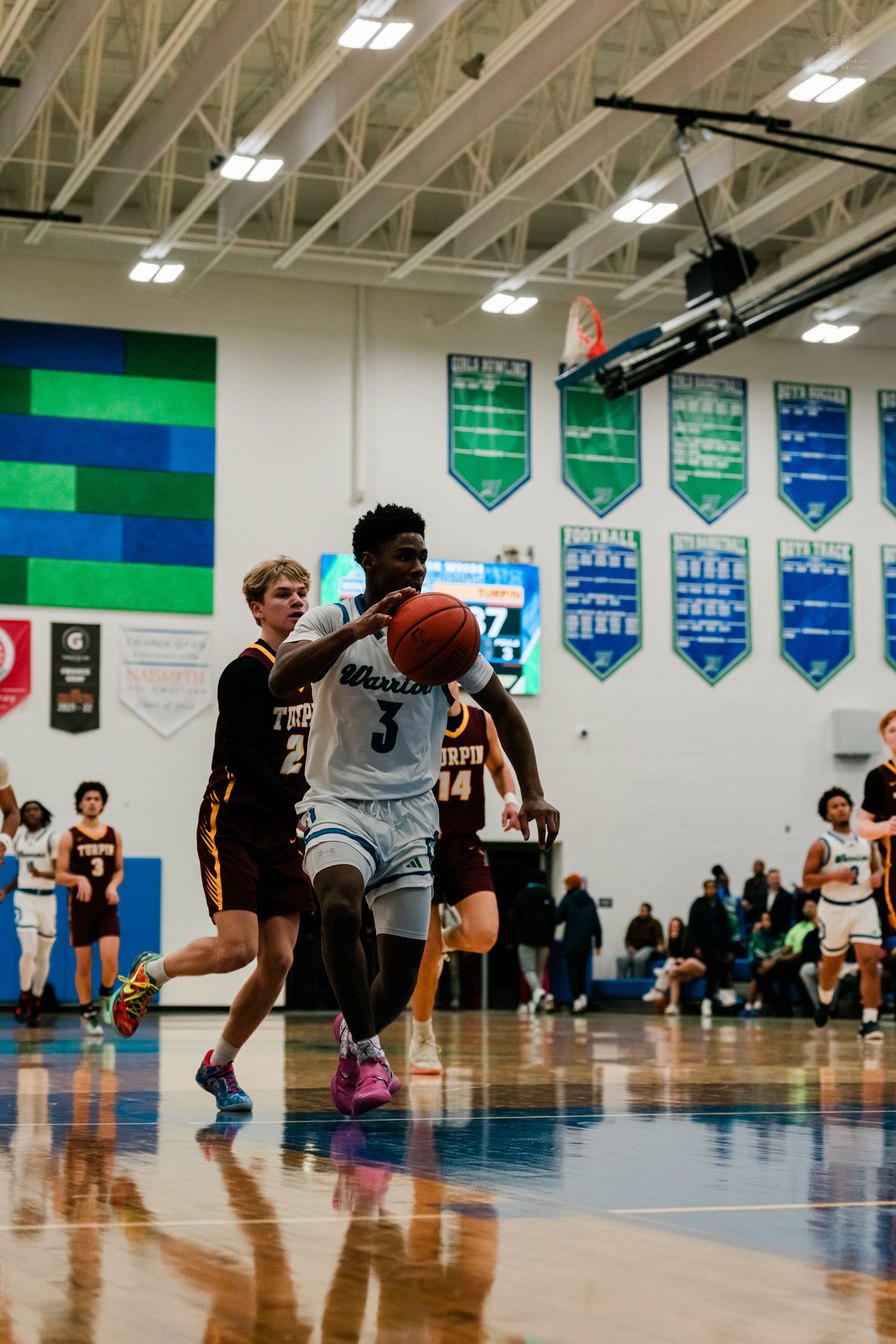 A Winton Woods player drives baseline past a Turpin defender toward the basket during a high school basketball game.