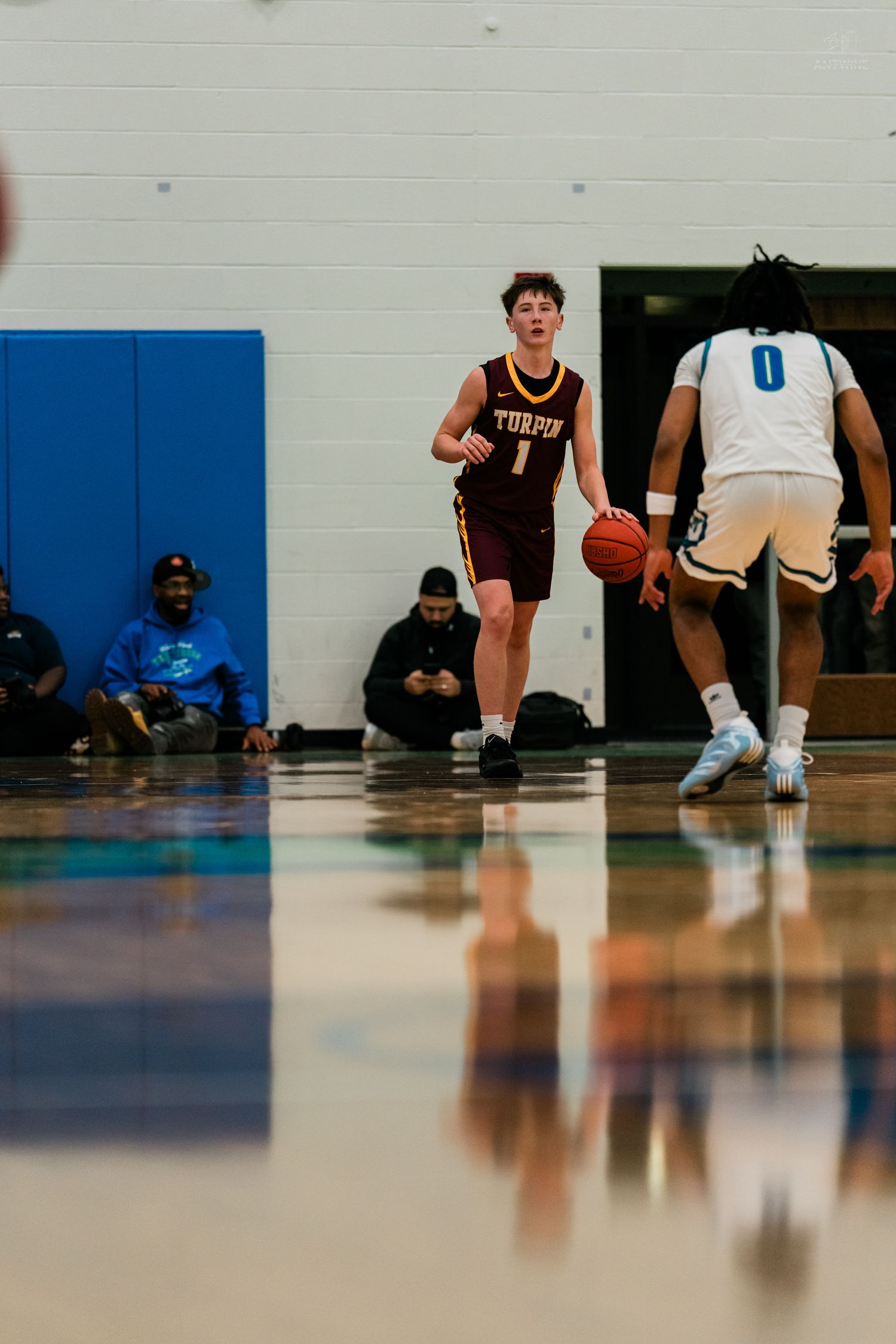 Turpin basketball player #1 sets up offense against Warriors #0 during high school varsity basketball game.