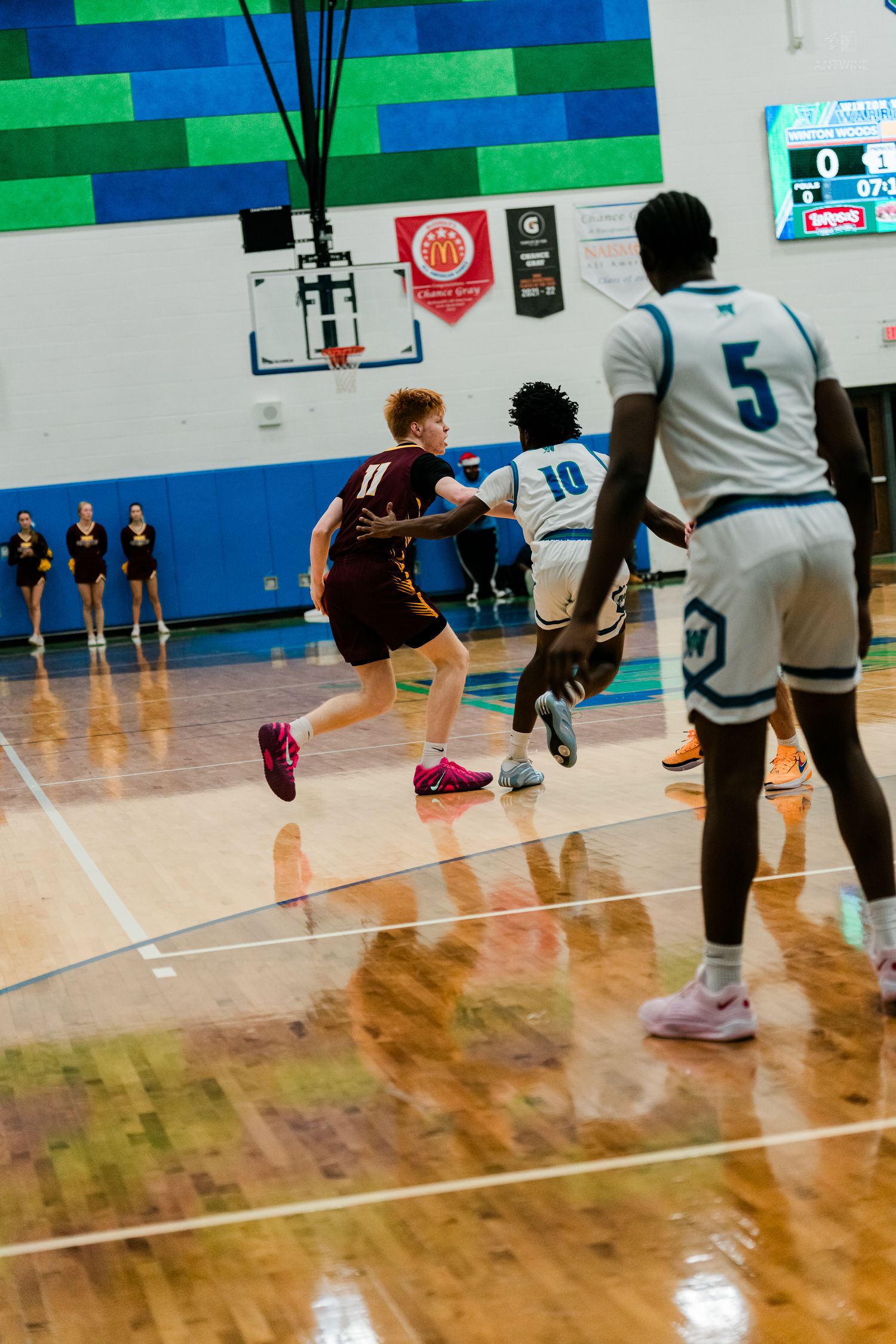 High school basketball players compete on a polished hardwood court during an intense game at Winton Woods gymnasium.
