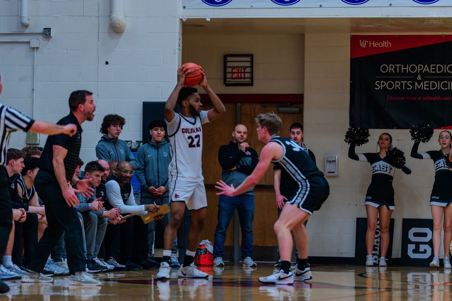 Basketball player number 22 in white uniform holds ball near sideline during a high school game.