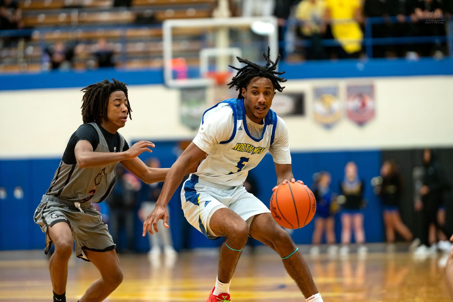 Warrior basketball player #4 drives past defender during fast-paced high school indoor basketball game.