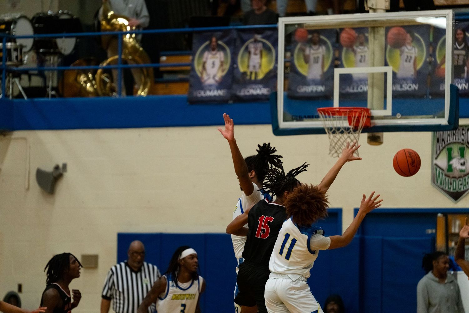 Basketball player in white number 11 jersey attempts a shot while being defended during a high school game.