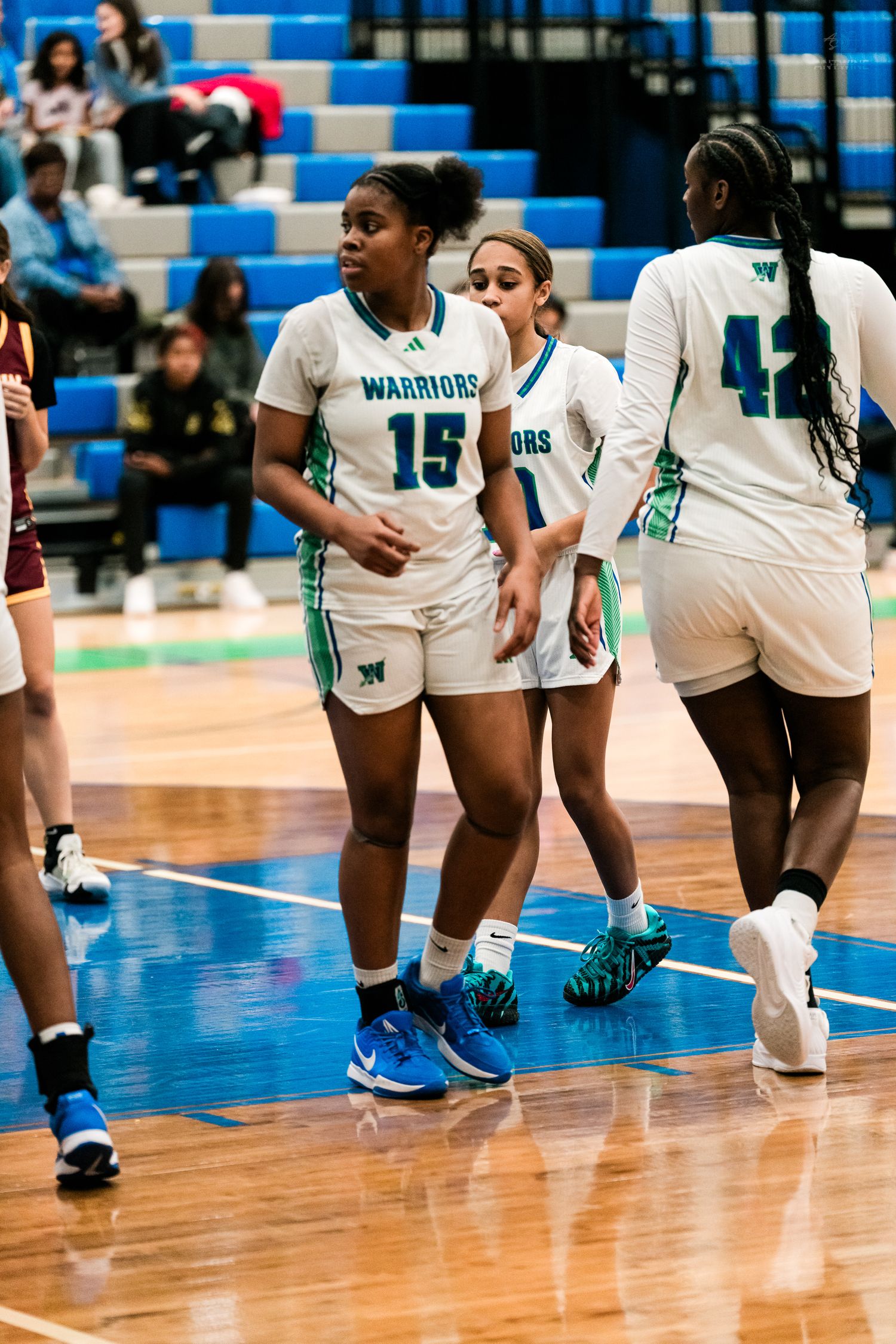Warriors girls basketball players #15 and #42 walk together on the court during a game.