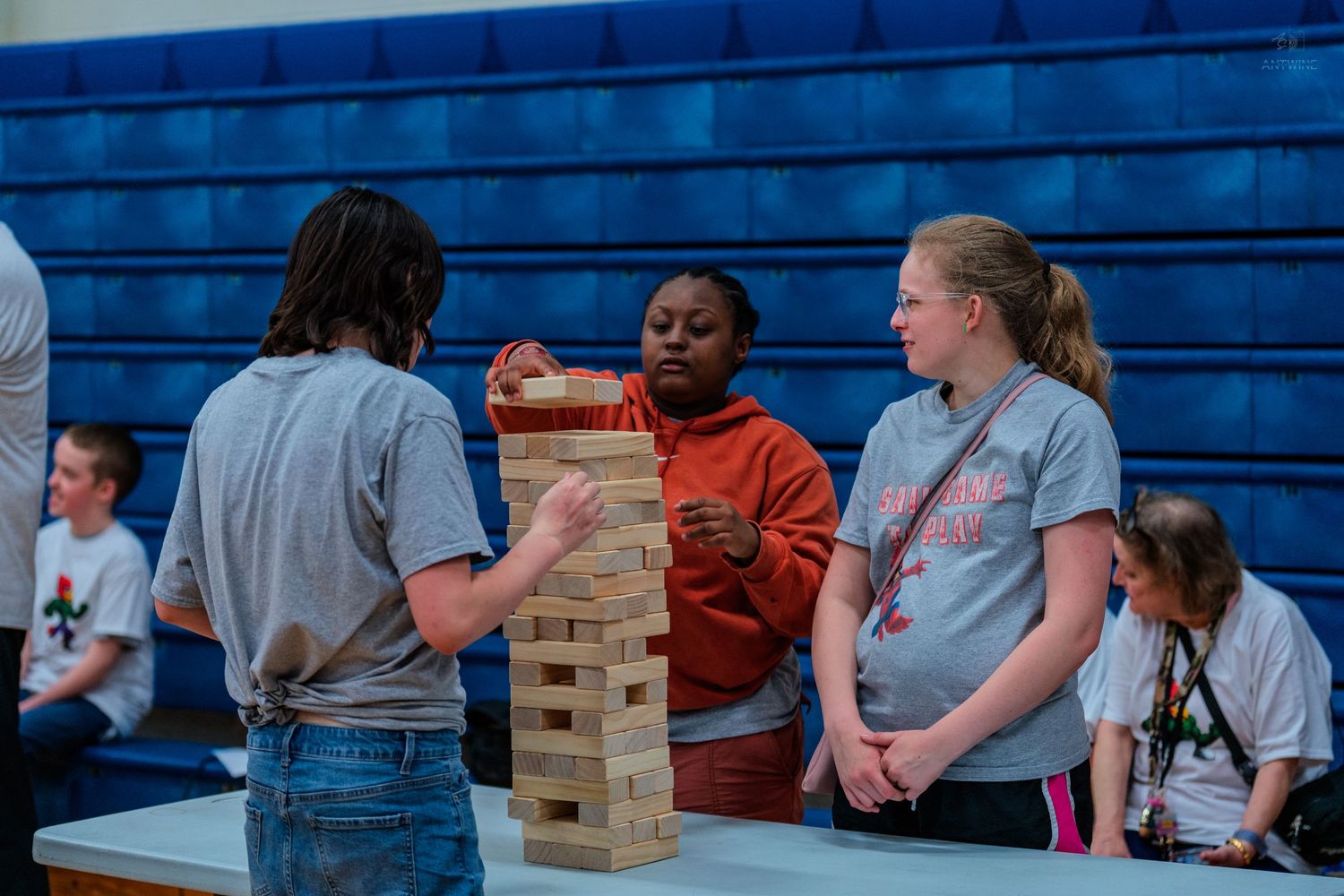 Students playing a giant Jenga game in a school gymnasium during an indoor activity event.