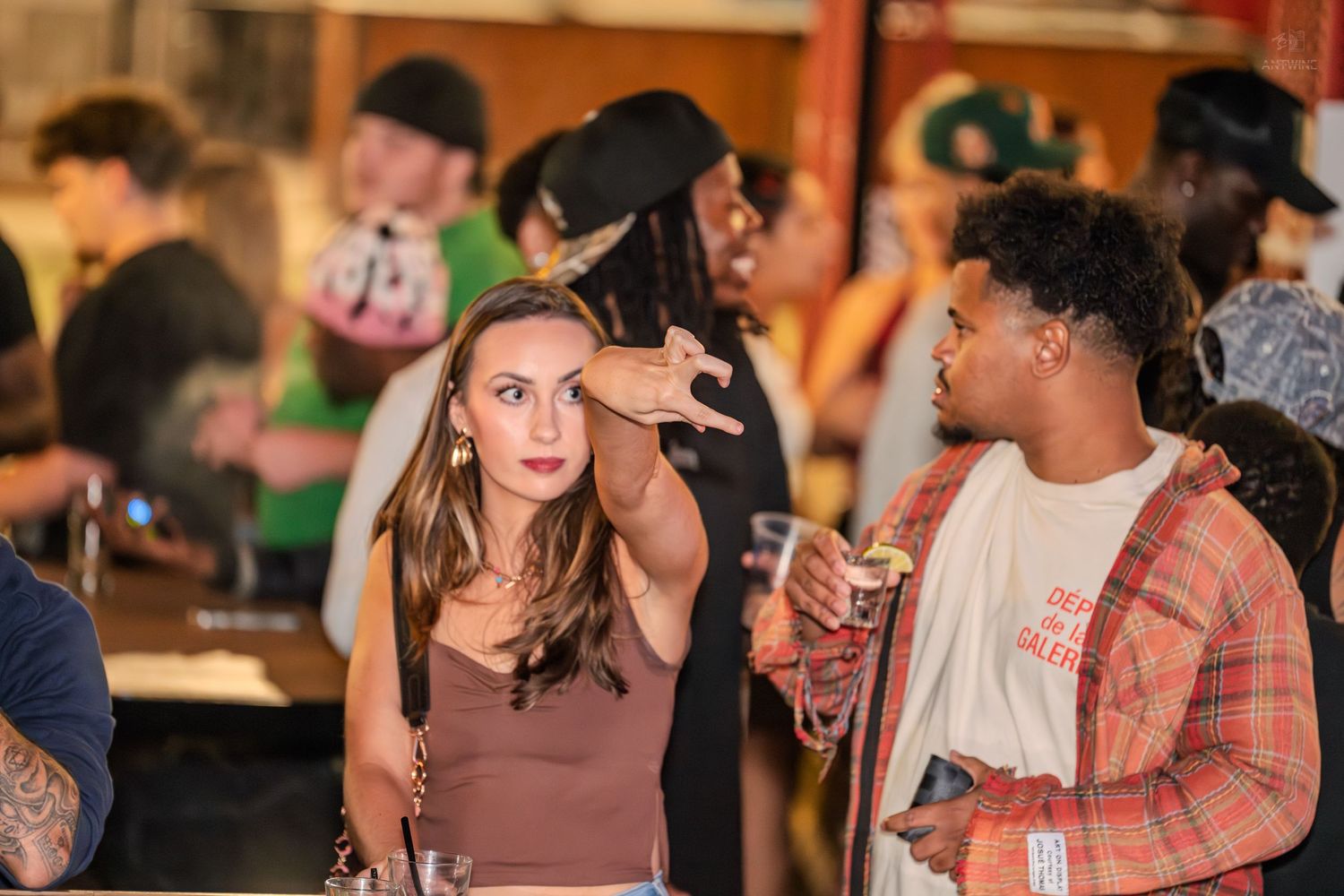 Woman pointing at her forehead while talking to a man at a party.