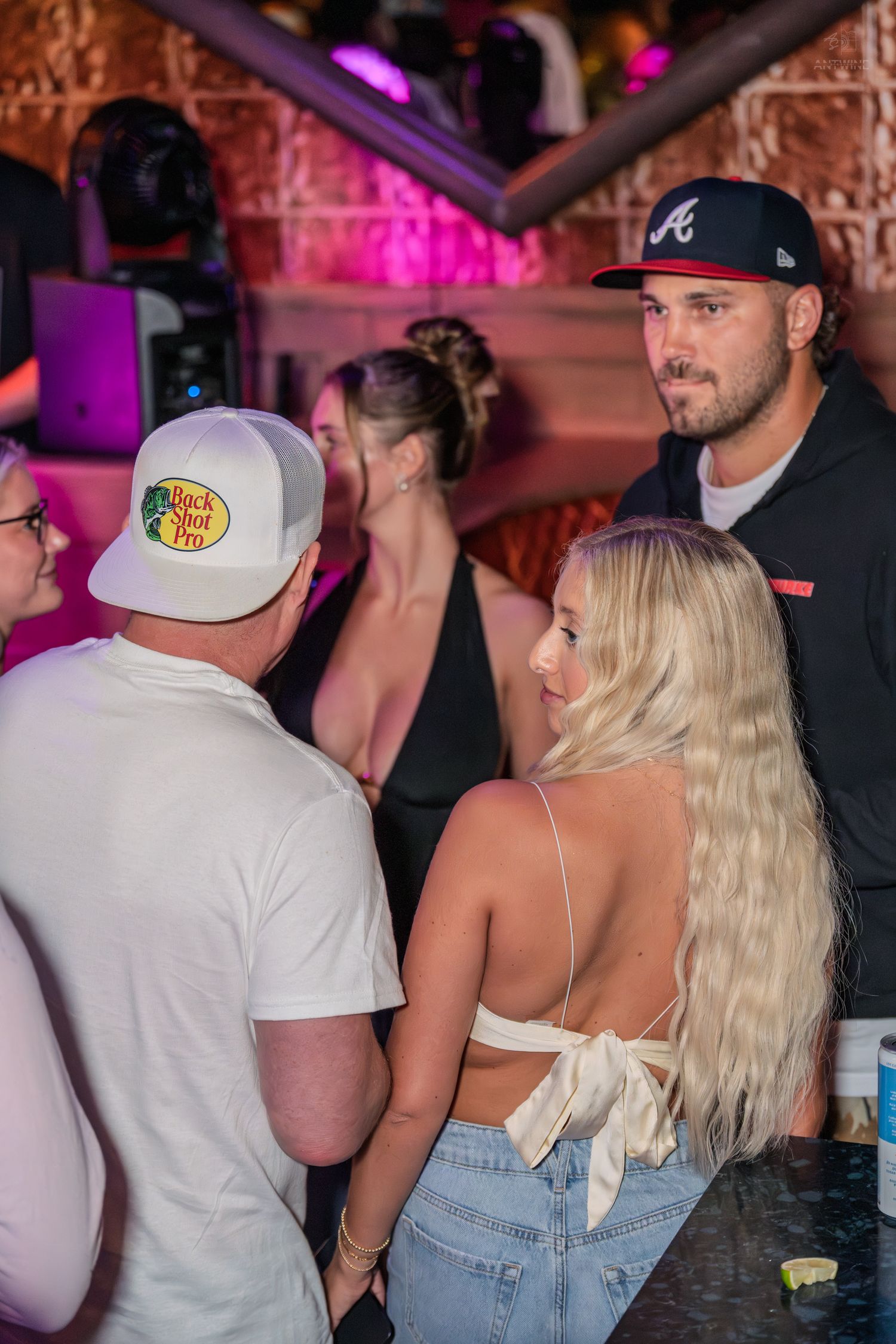 Group of people socializing near a DJ booth at a vibrant nightclub event.