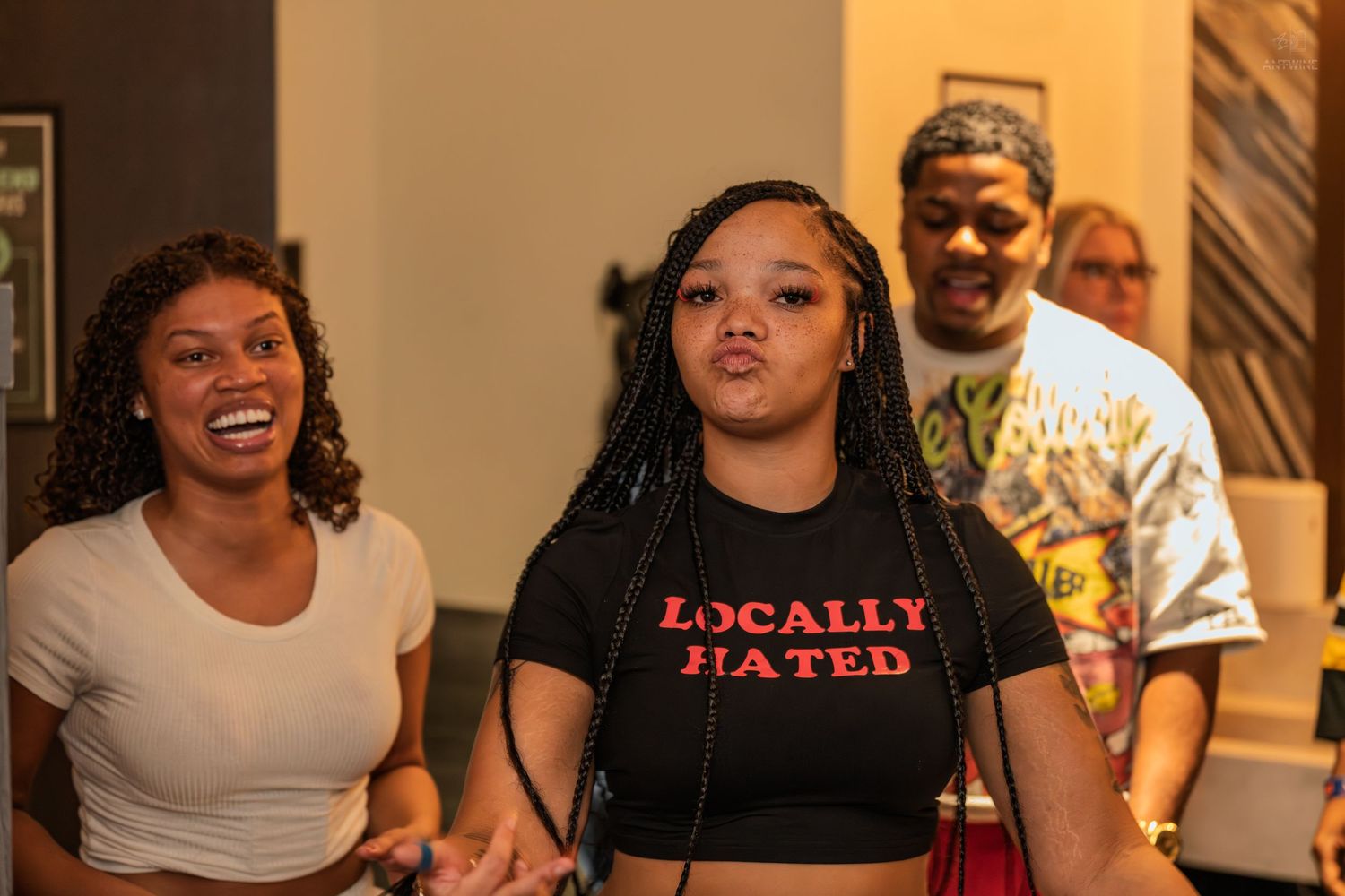 Three friends laughing together at a casual indoor social gathering.