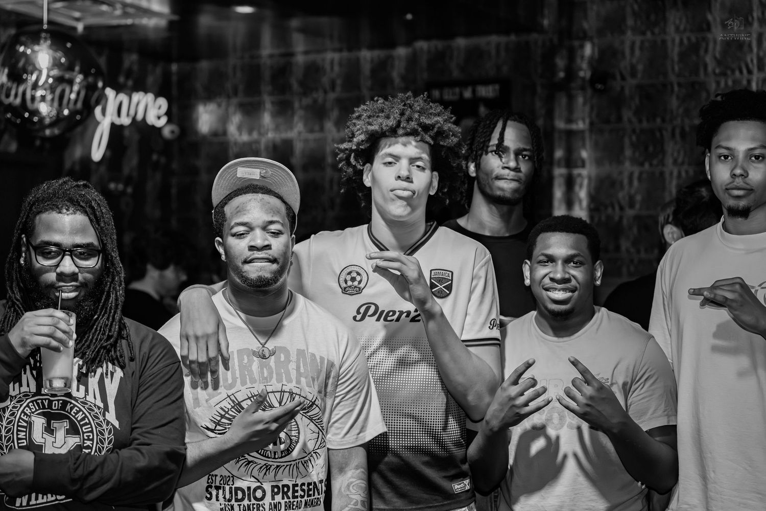 Black and white photo of a group of young men at an indoor music event.