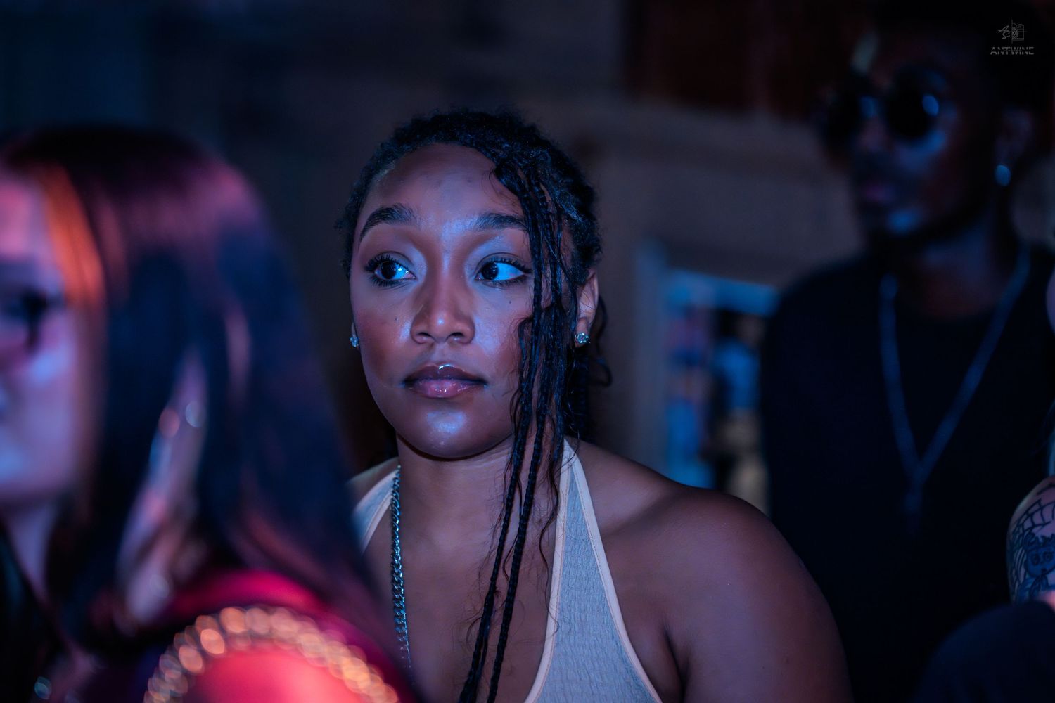 Close-up portrait of woman with braids and blue eyeshadow at nightclub event.