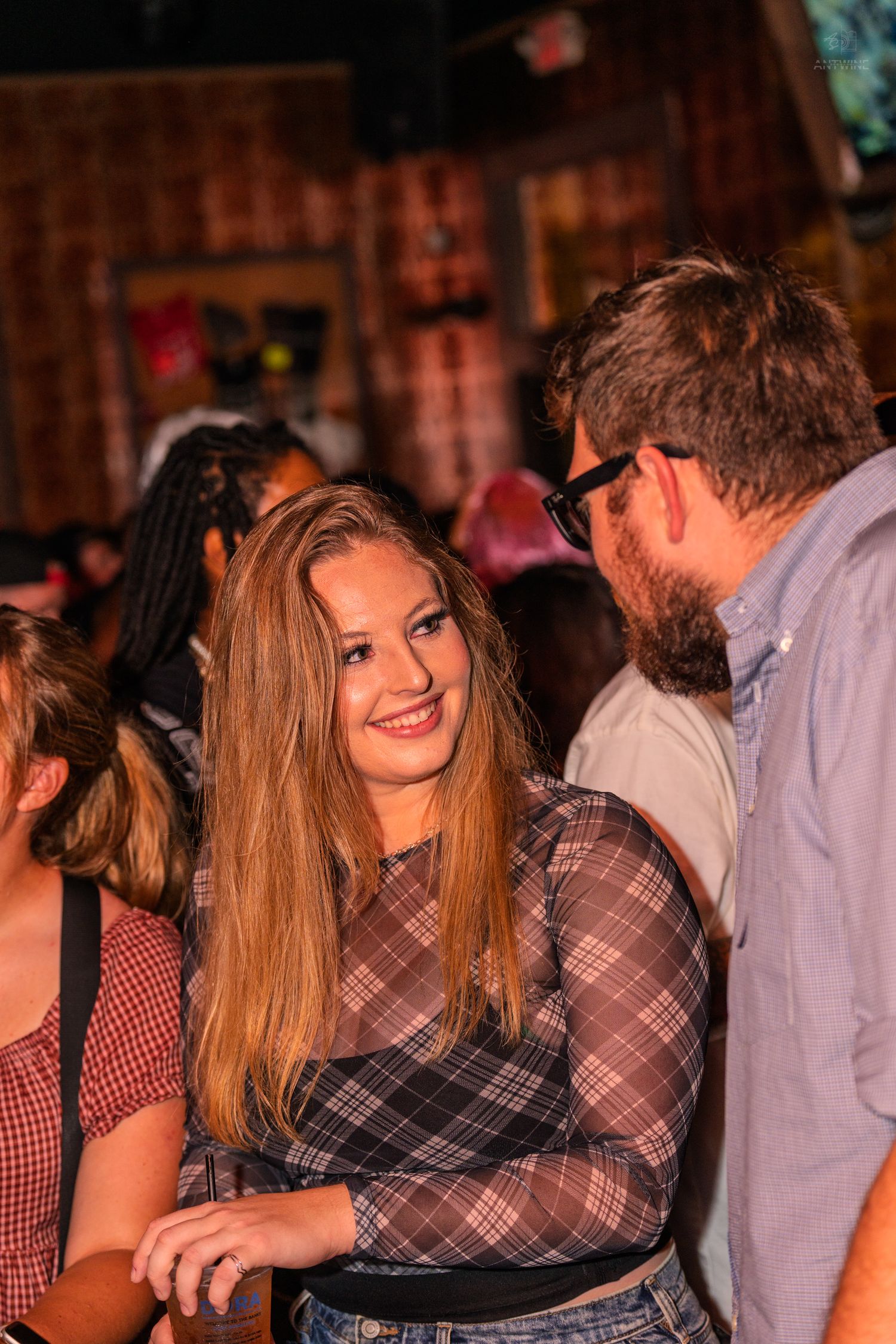 Smiling young woman with long hair chatting with a bearded man at a bar.