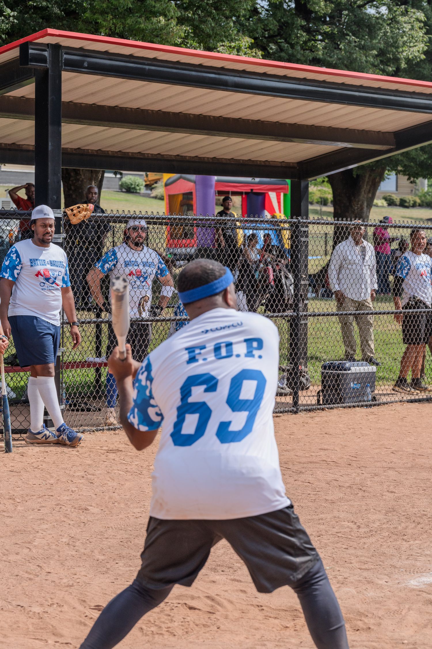 F.O.P. #69 batter prepares to swing during a softball game as spectators watch from behind a fence.