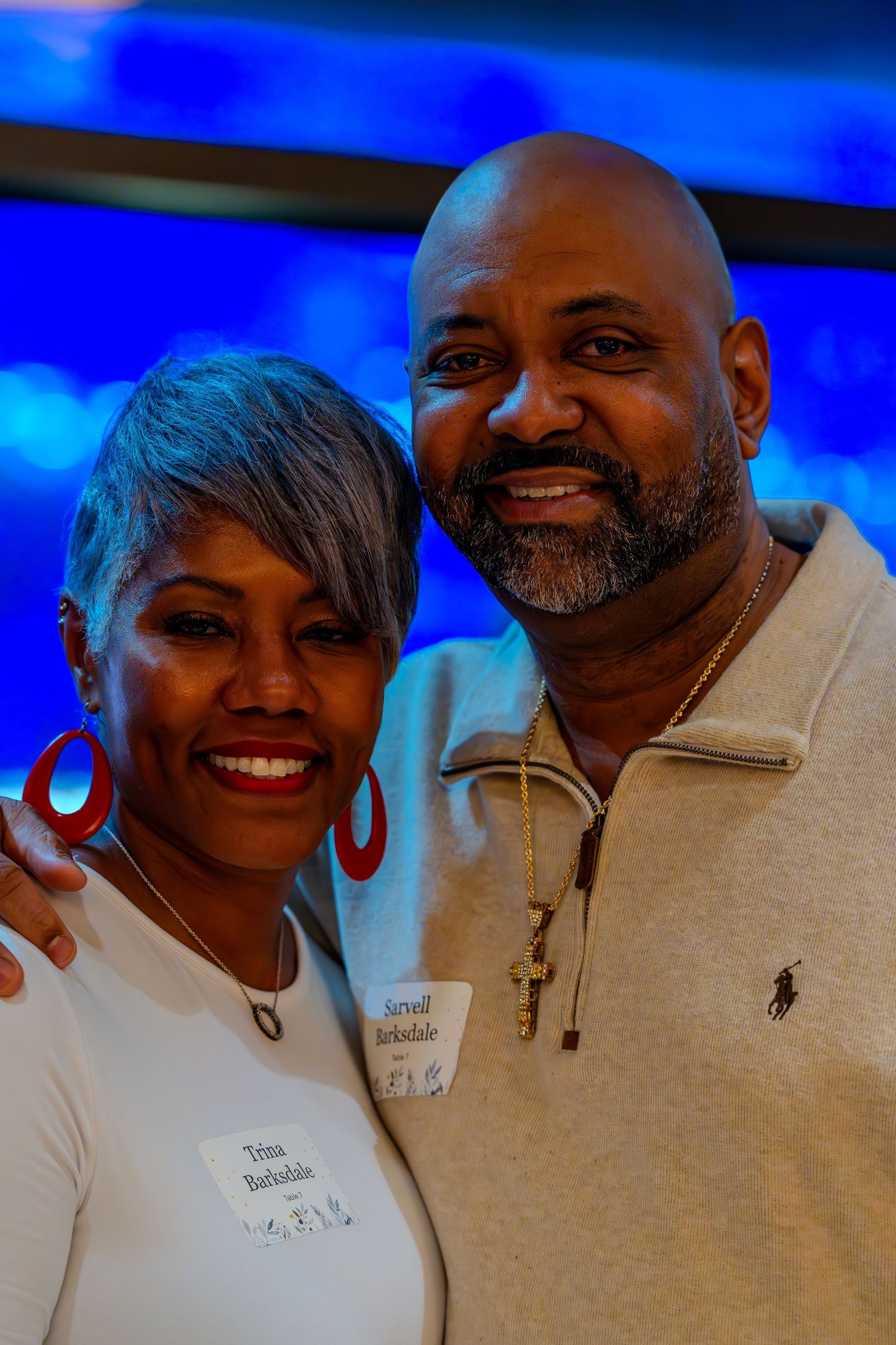 Trina and Jermal Barksdale smiling together at an event, wearing name tags and casual attire.