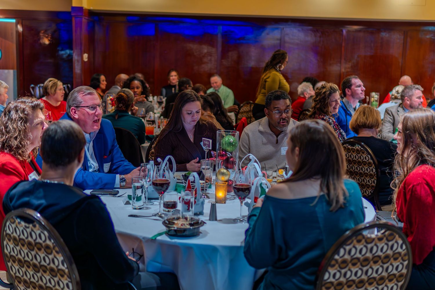 Guests networking at a formal banquet dinner event, seated at round tables in an elegant banquet hall.