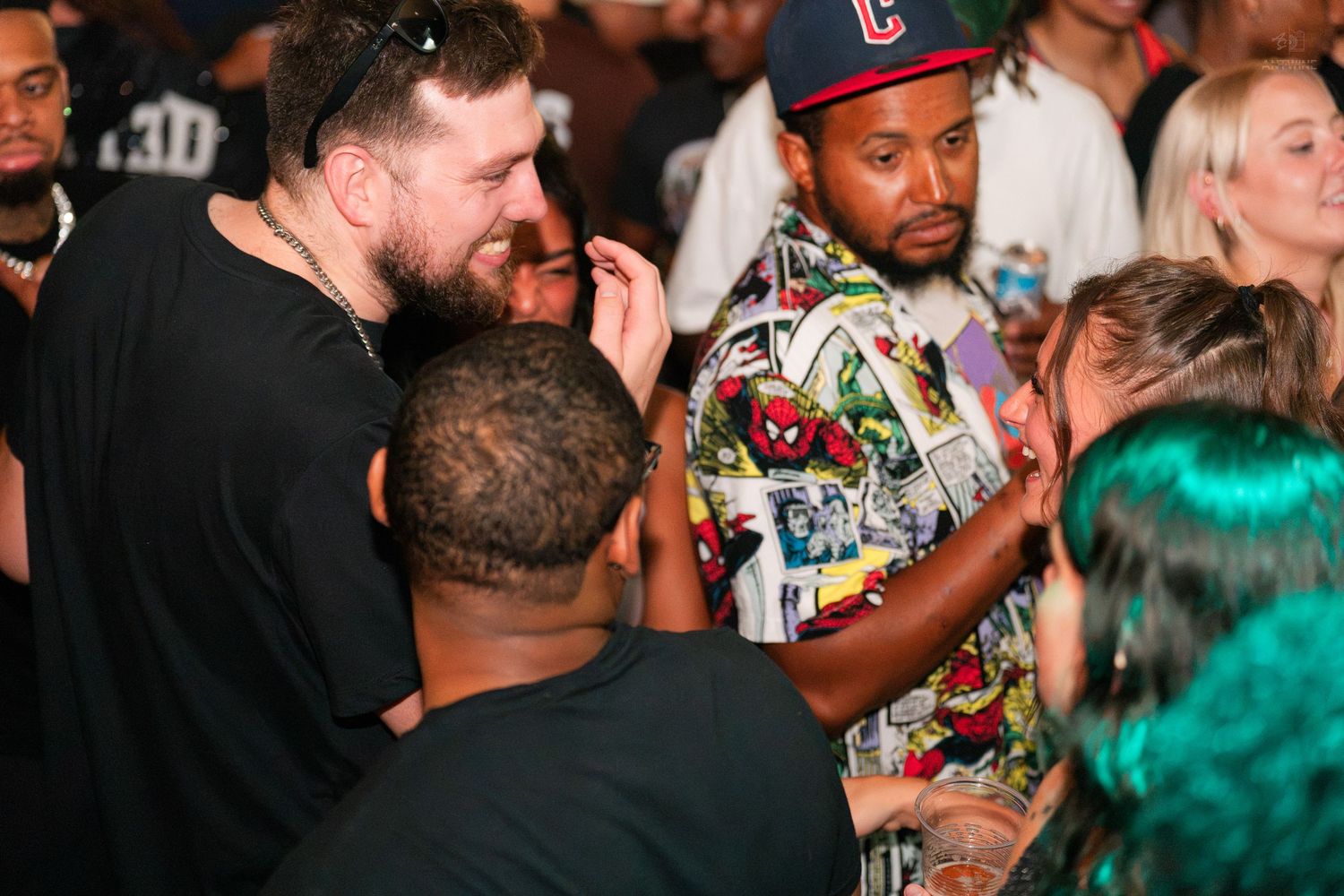 Group of men socializing closely together in a crowded nightclub or party venue.