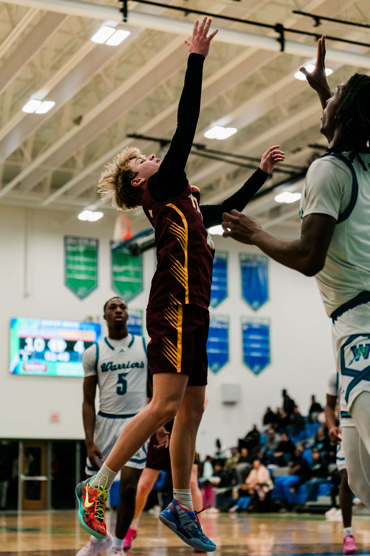 Turpin basketball player attempts layup while being contested by Warriors defender during high school game.