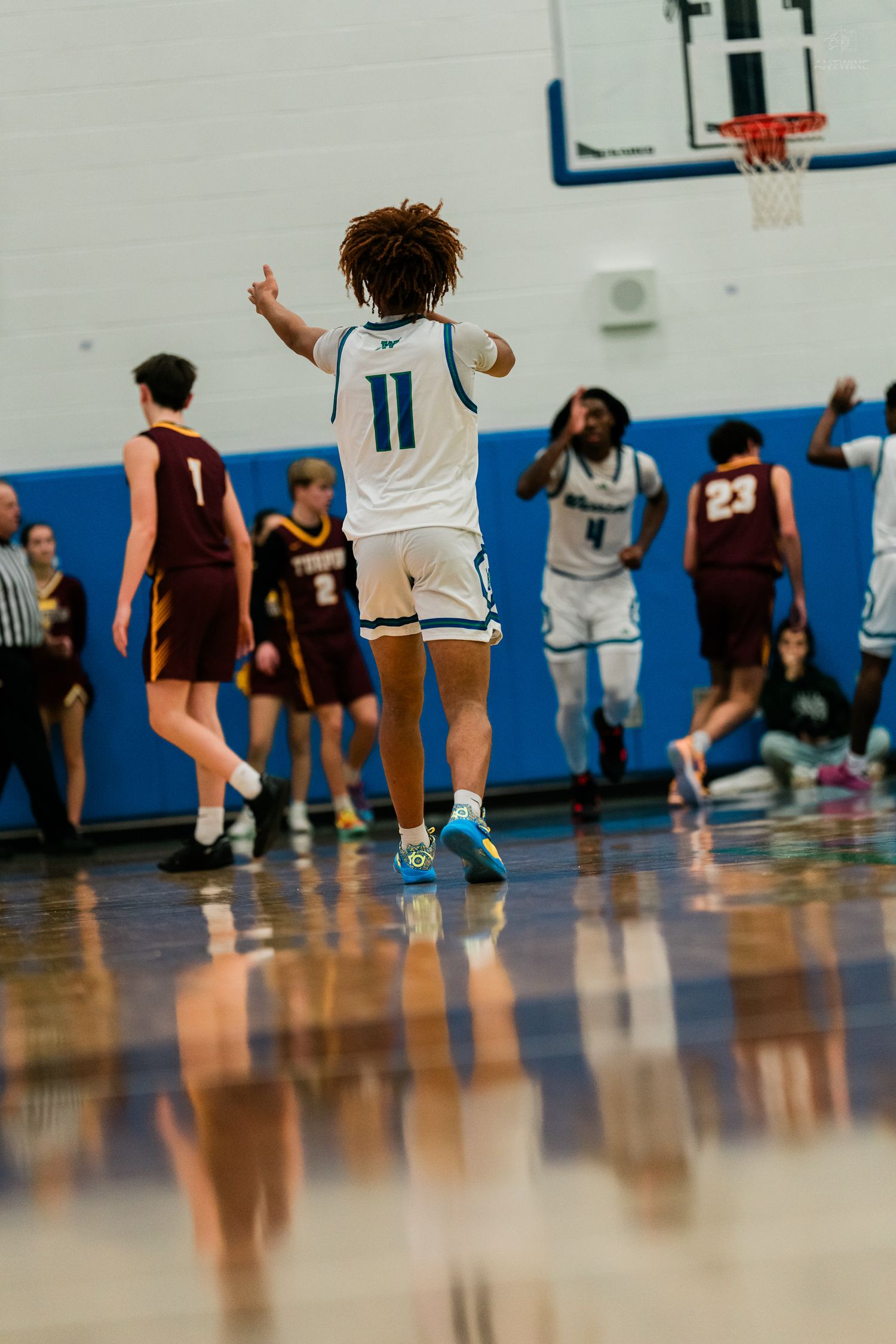 Warriors #11 celebrates with a thumbs up after a successful play during a high school basketball game.