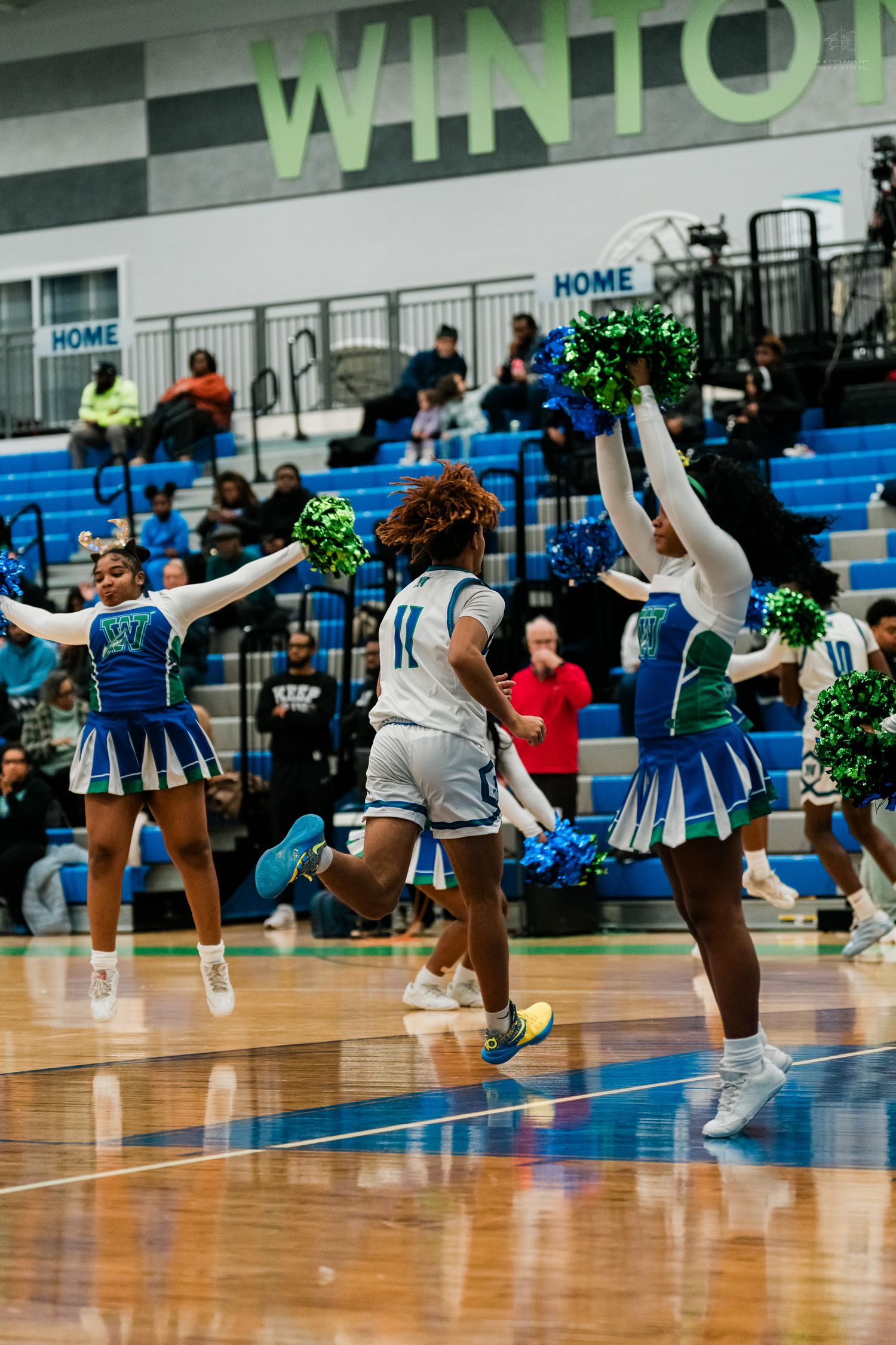 Basketball player #11 runs through cheering squad tunnel during pregame introductions at Winton gym.