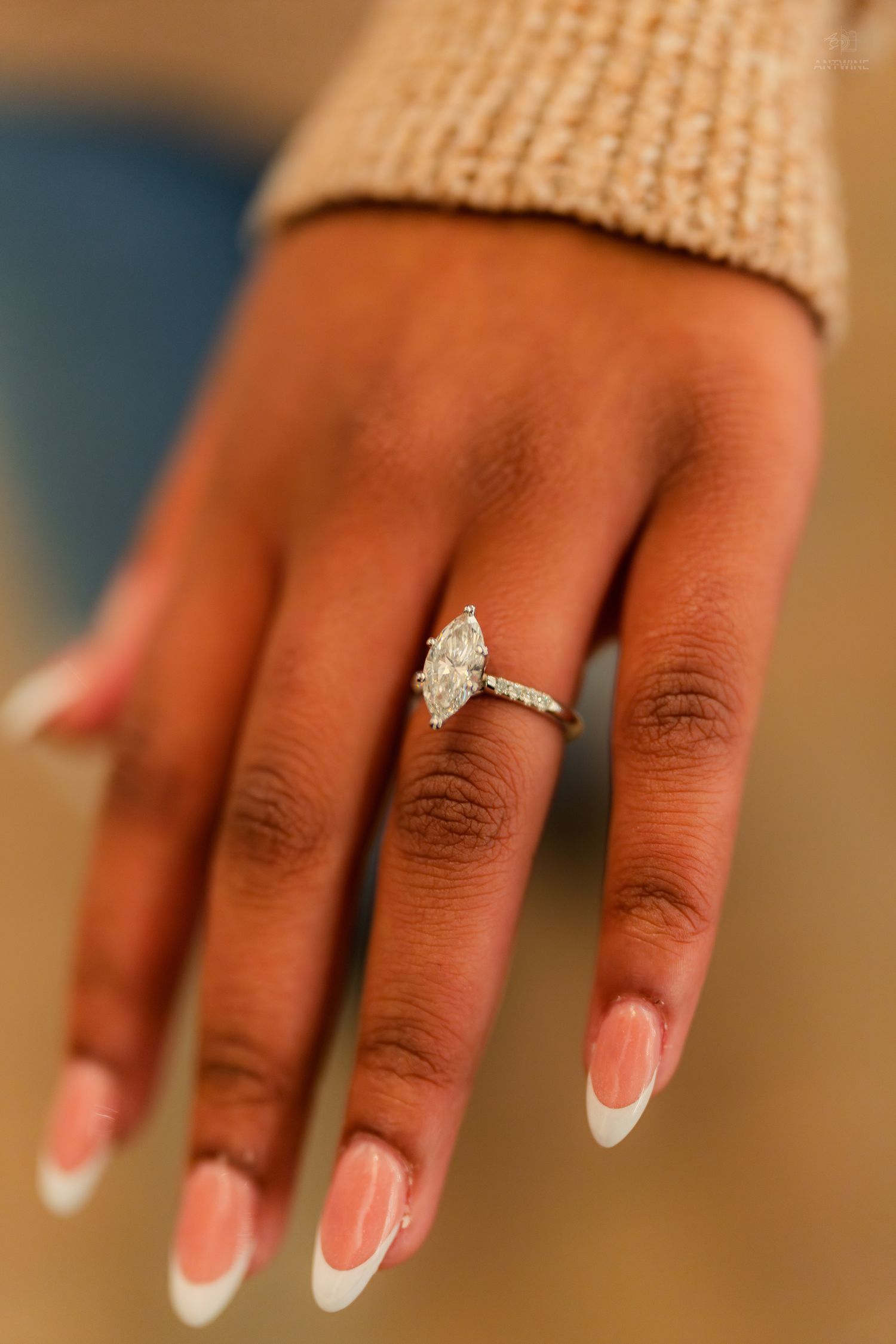 Close-up of a marquise diamond engagement ring on a hand with French manicured nails.