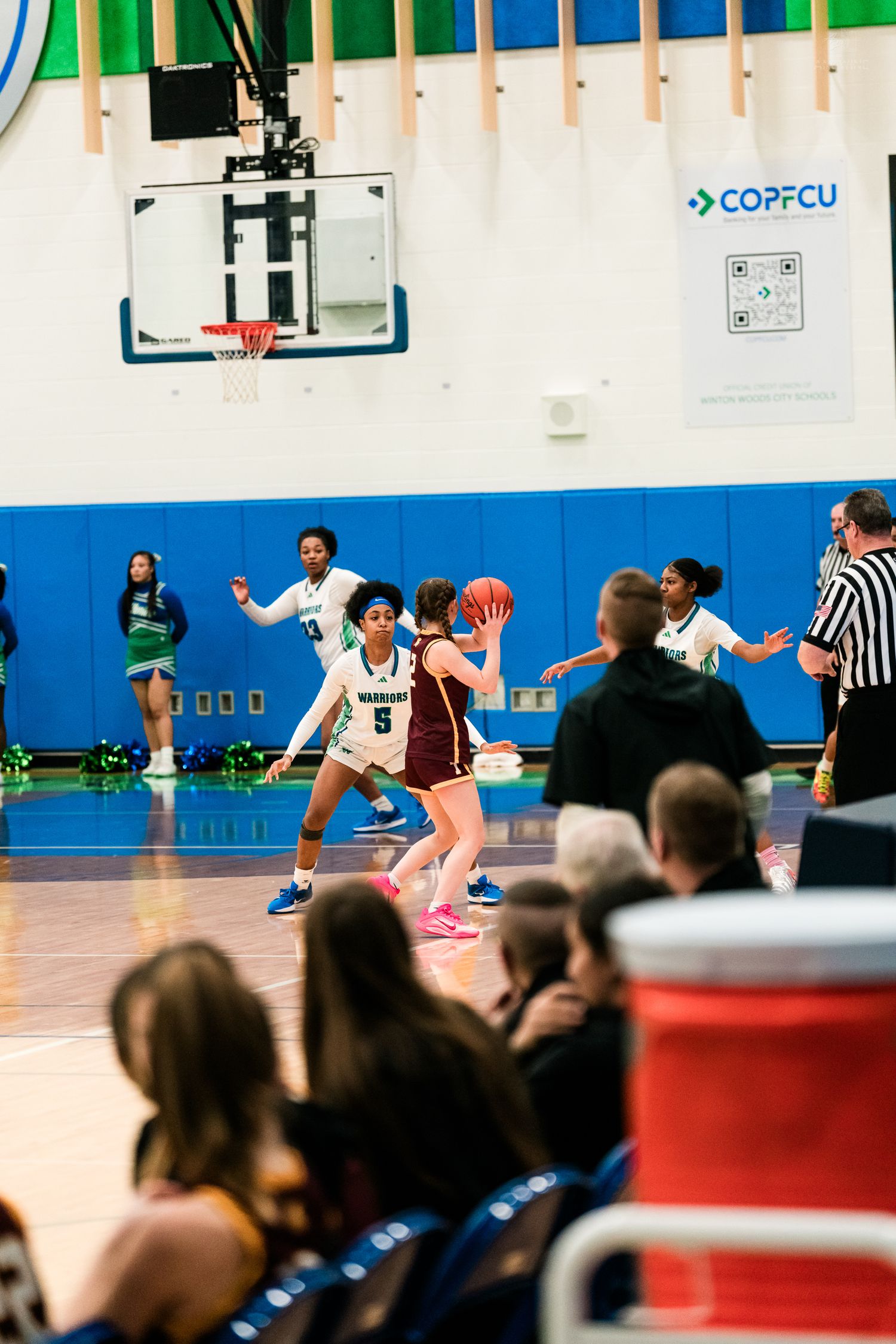 A defender in white jersey number 5 guards a player with the ball in a girls high school basketball game.
