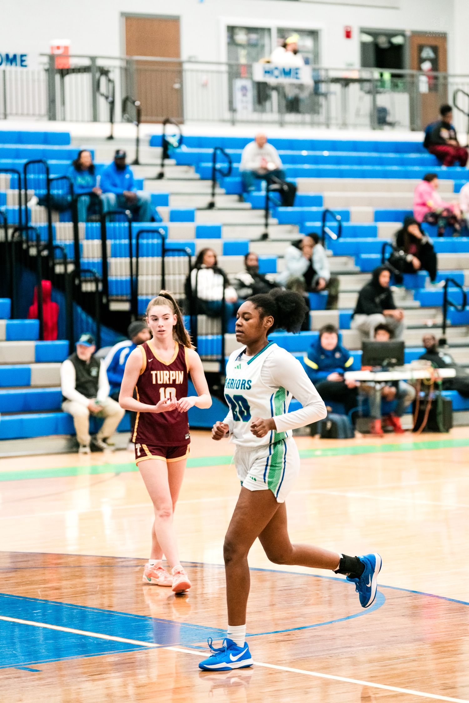 Female basketball players from Turpin and home team run down the court during a high school girls basketball game.