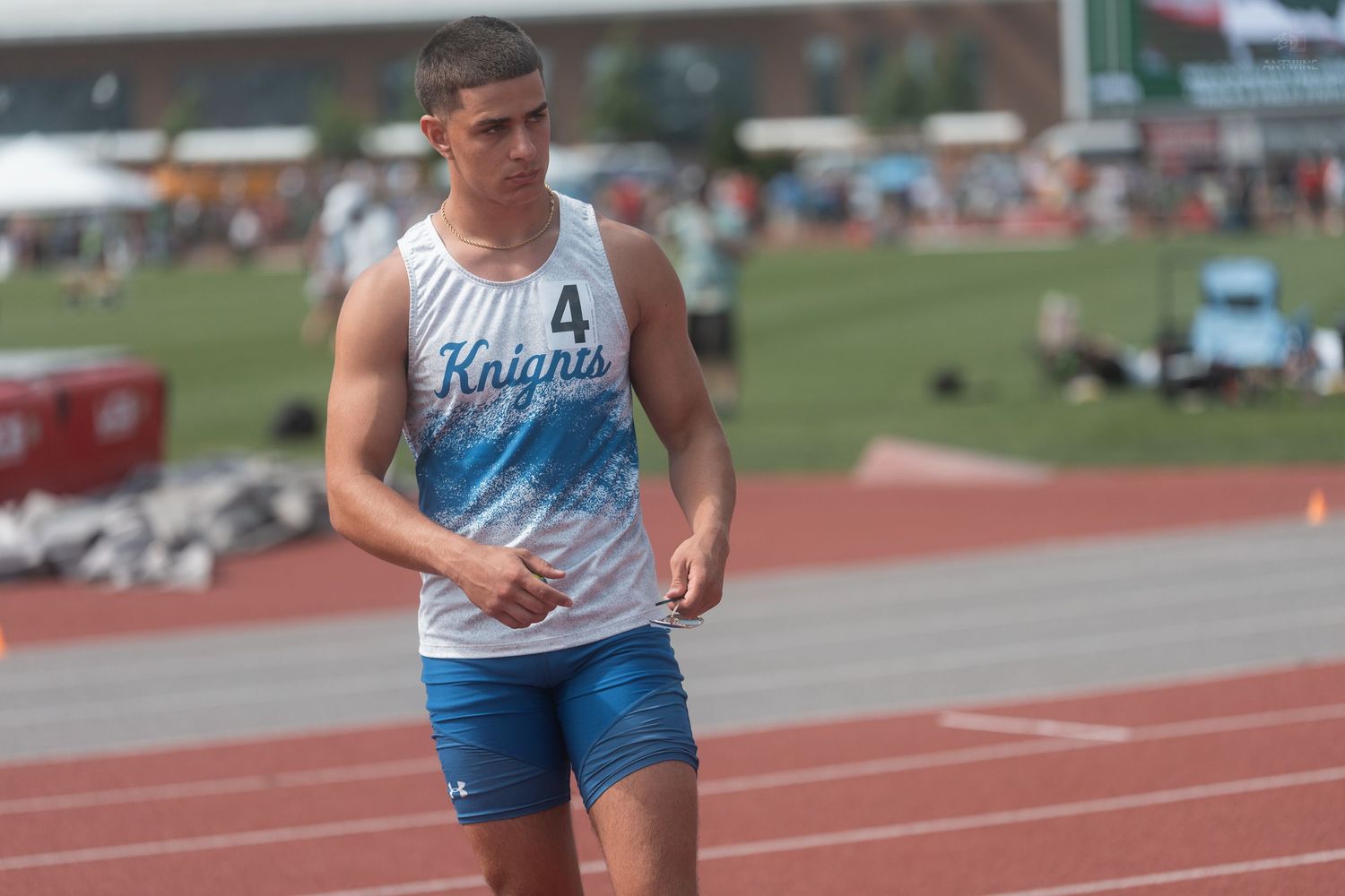 Close-up of male Knights track athlete number 4 in sleeveless uniform at outdoor track competition.