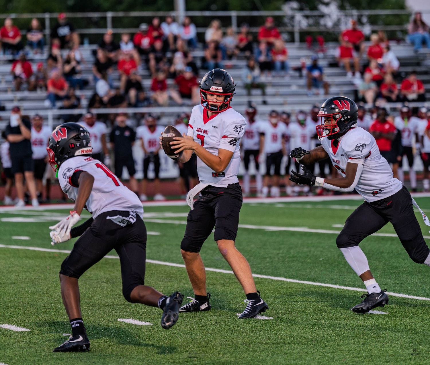 A quarterback prepares to throw a pass while teammates block during a high school football game.