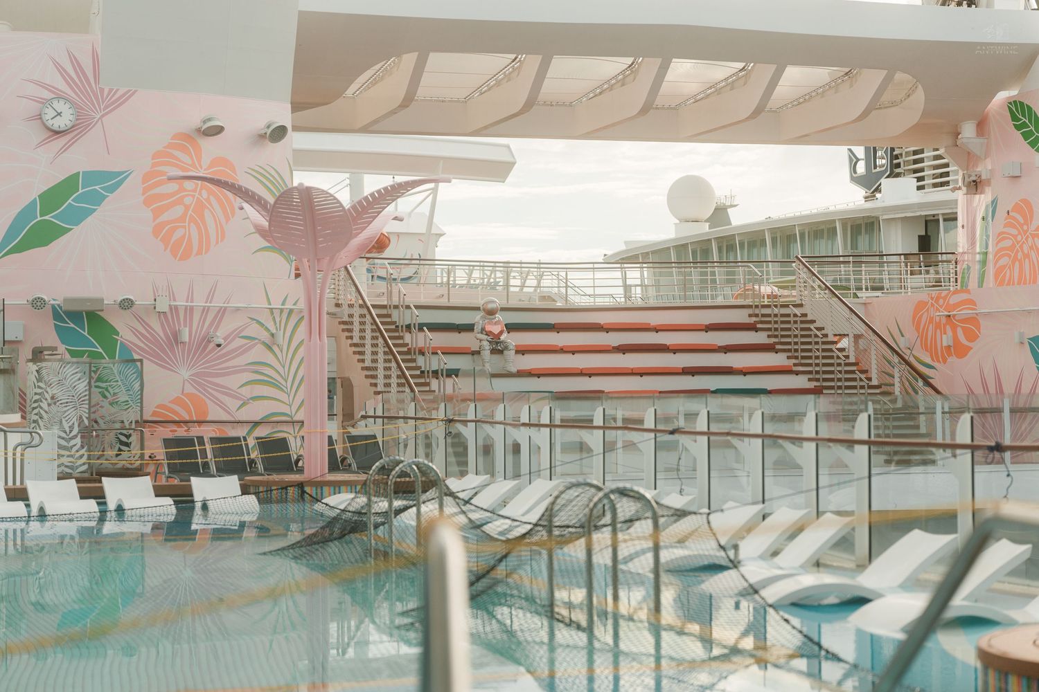 A serene cruise ship pool deck featuring tropical pink flamingo murals and lounge chairs.
