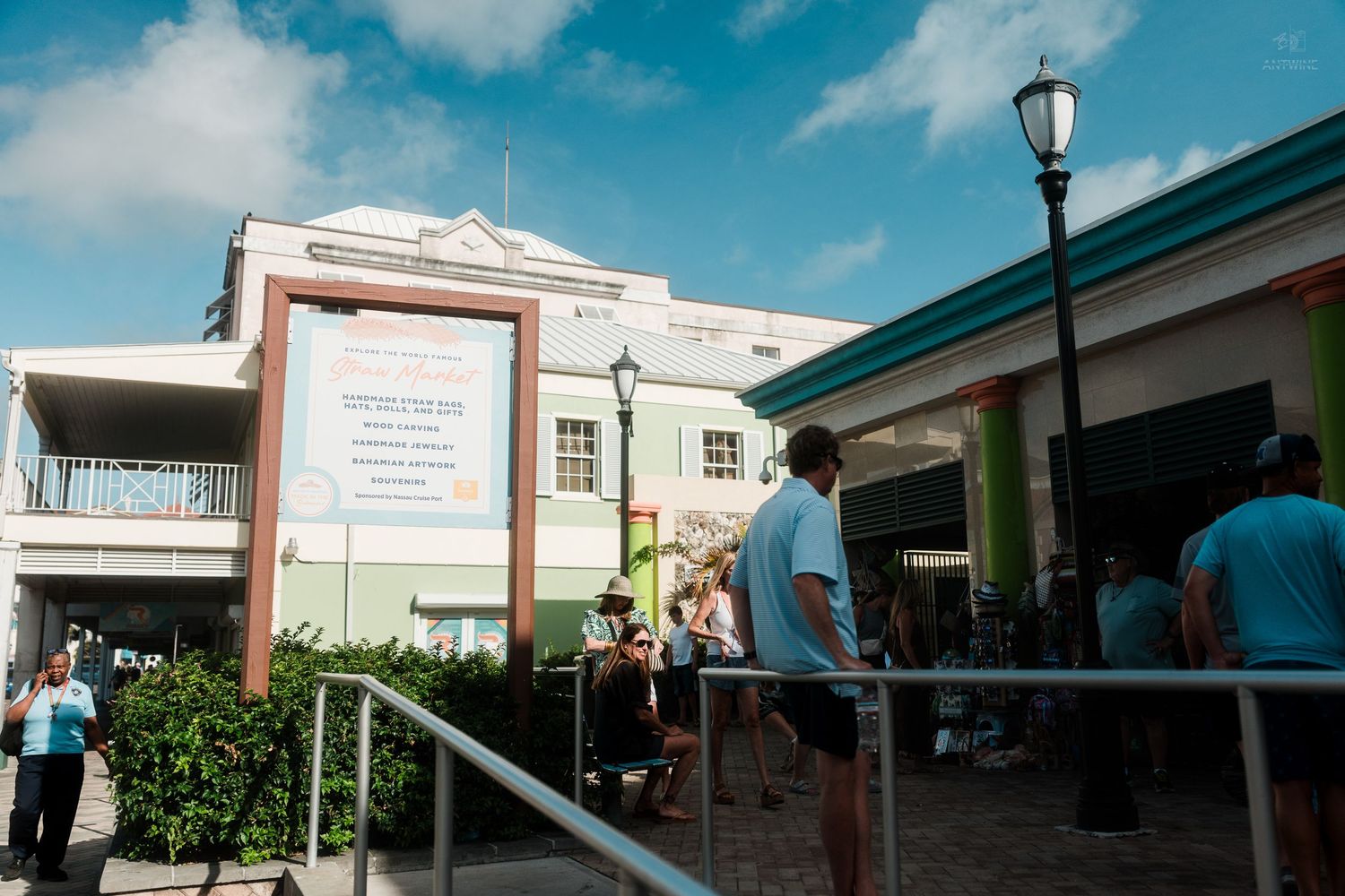 Tourists gathered outside a pastel green colonial building in a Caribbean port shopping district.