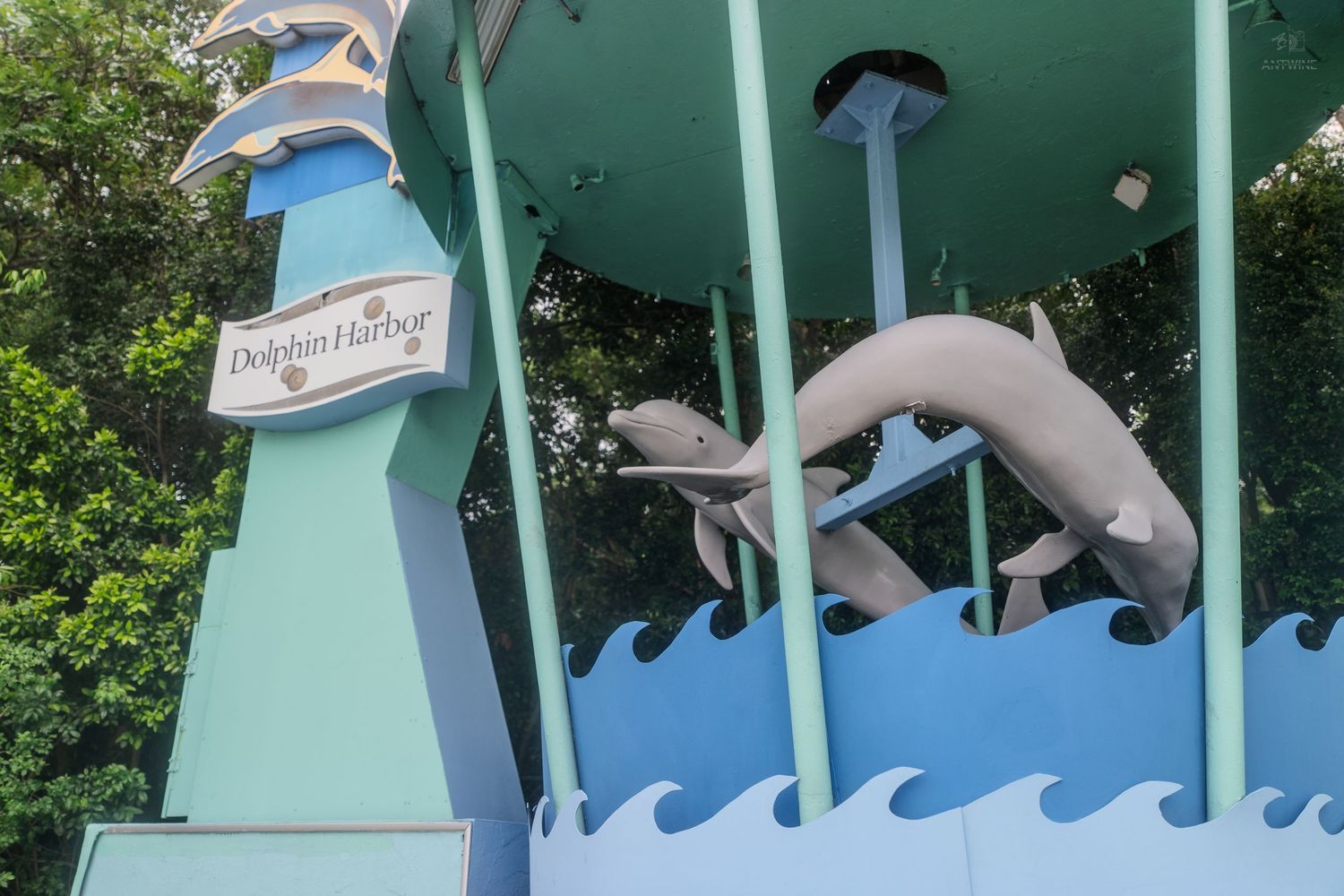 Dolphin Harbor attraction sign with decorative dolphin sculptures at a marine theme park entrance.