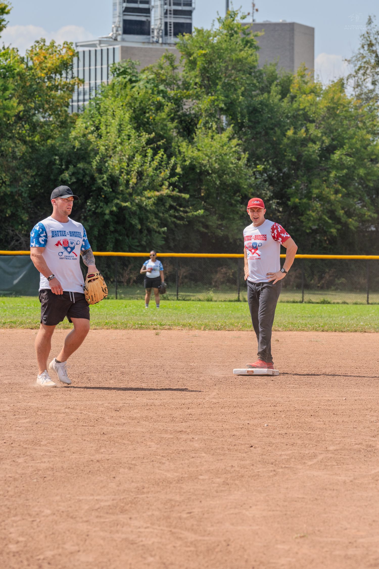 Two men in baseball uniforms standing on dirt infield during game.