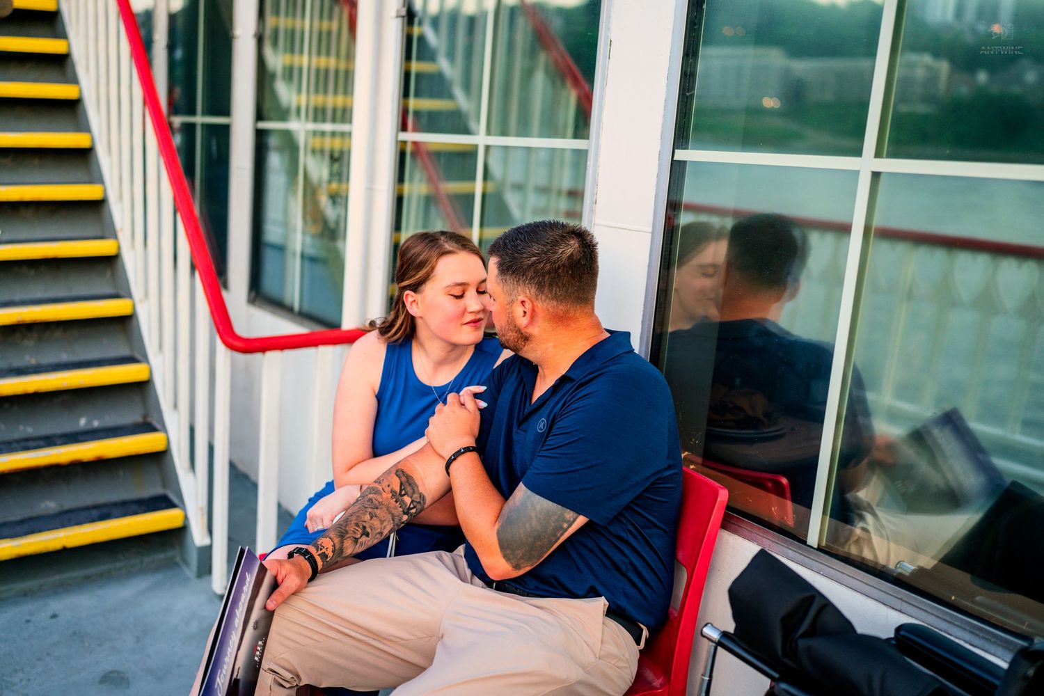 Couple sharing an intimate moment seated together on a colorful urban outdoor staircase at sunset.