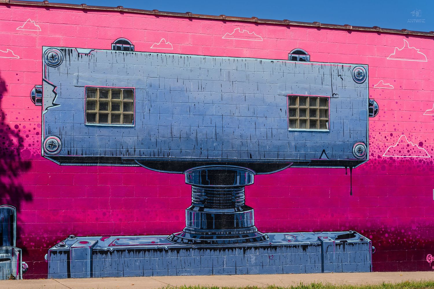 Vibrant pink building wall featuring a large gray industrial machine mural street art in an urban setting.