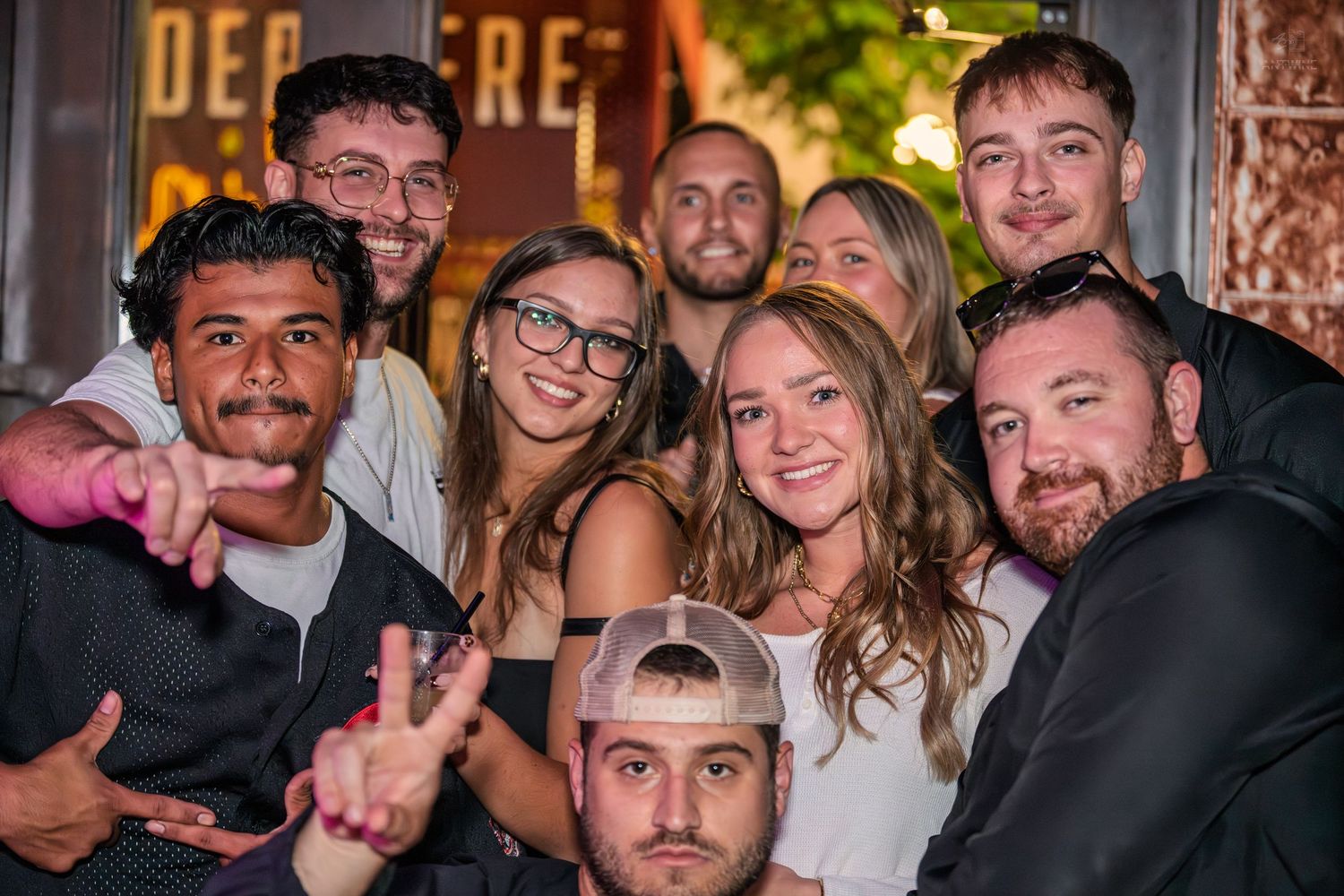 Happy group of friends posing together for a photo outside a bar at night.