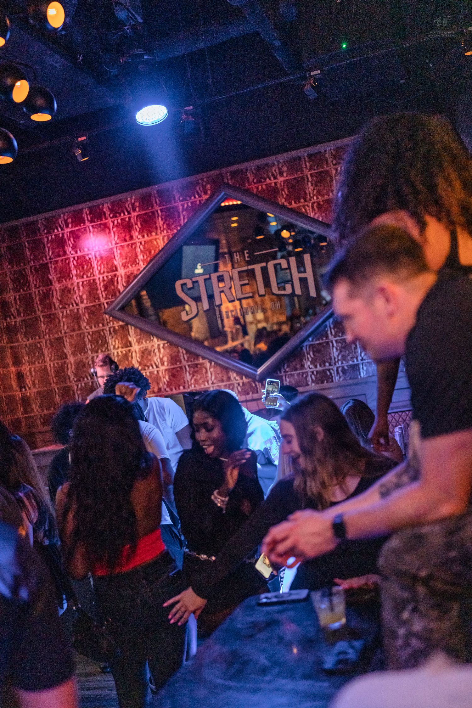 People dancing and socializing inside The Stretch nightclub under blue and red stage lighting.