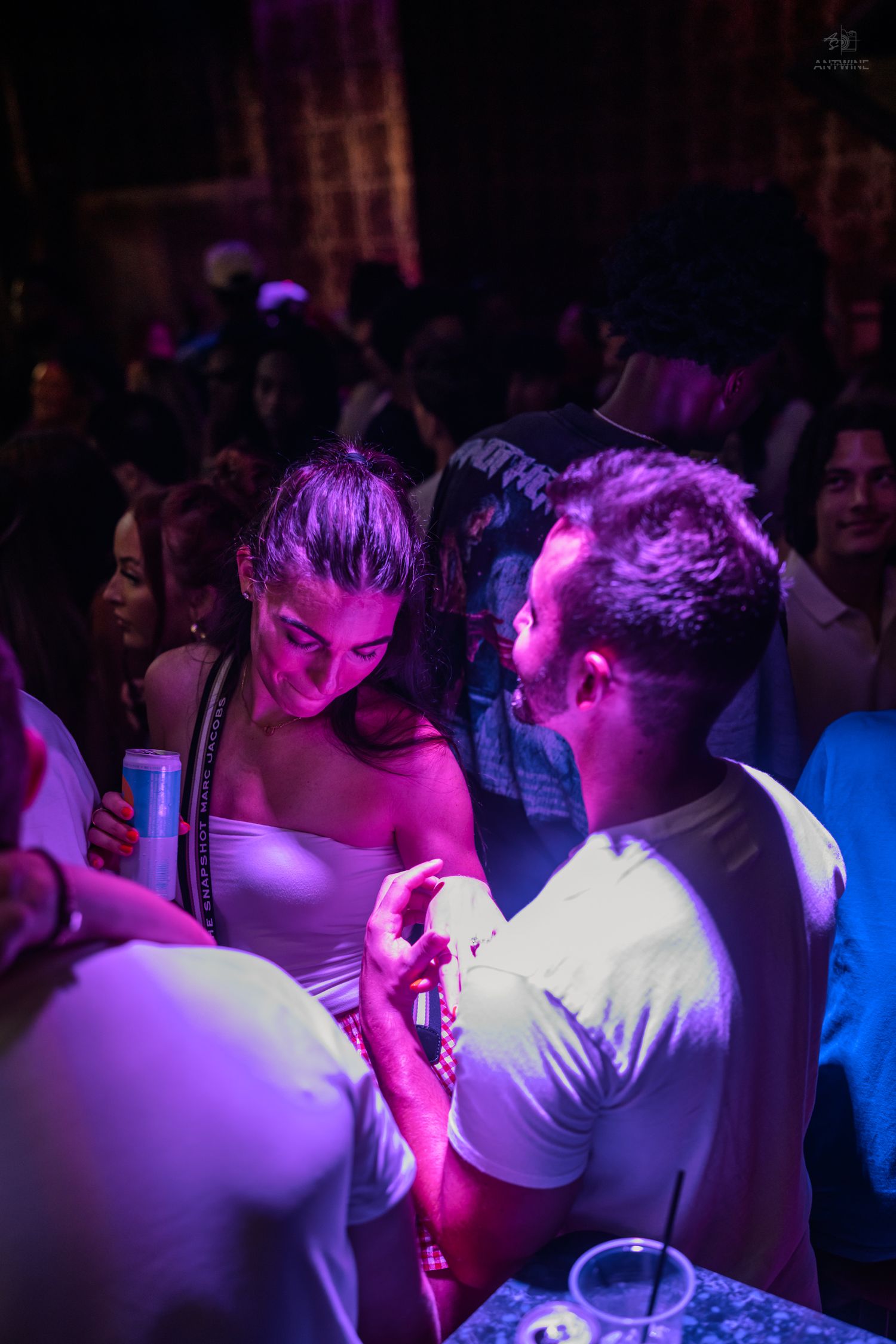Couple in white outfits sharing an intimate conversation at a nightclub.